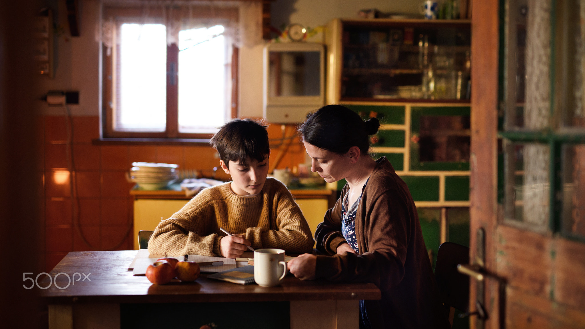 Poor mature mother and small daughter learning indoors at home