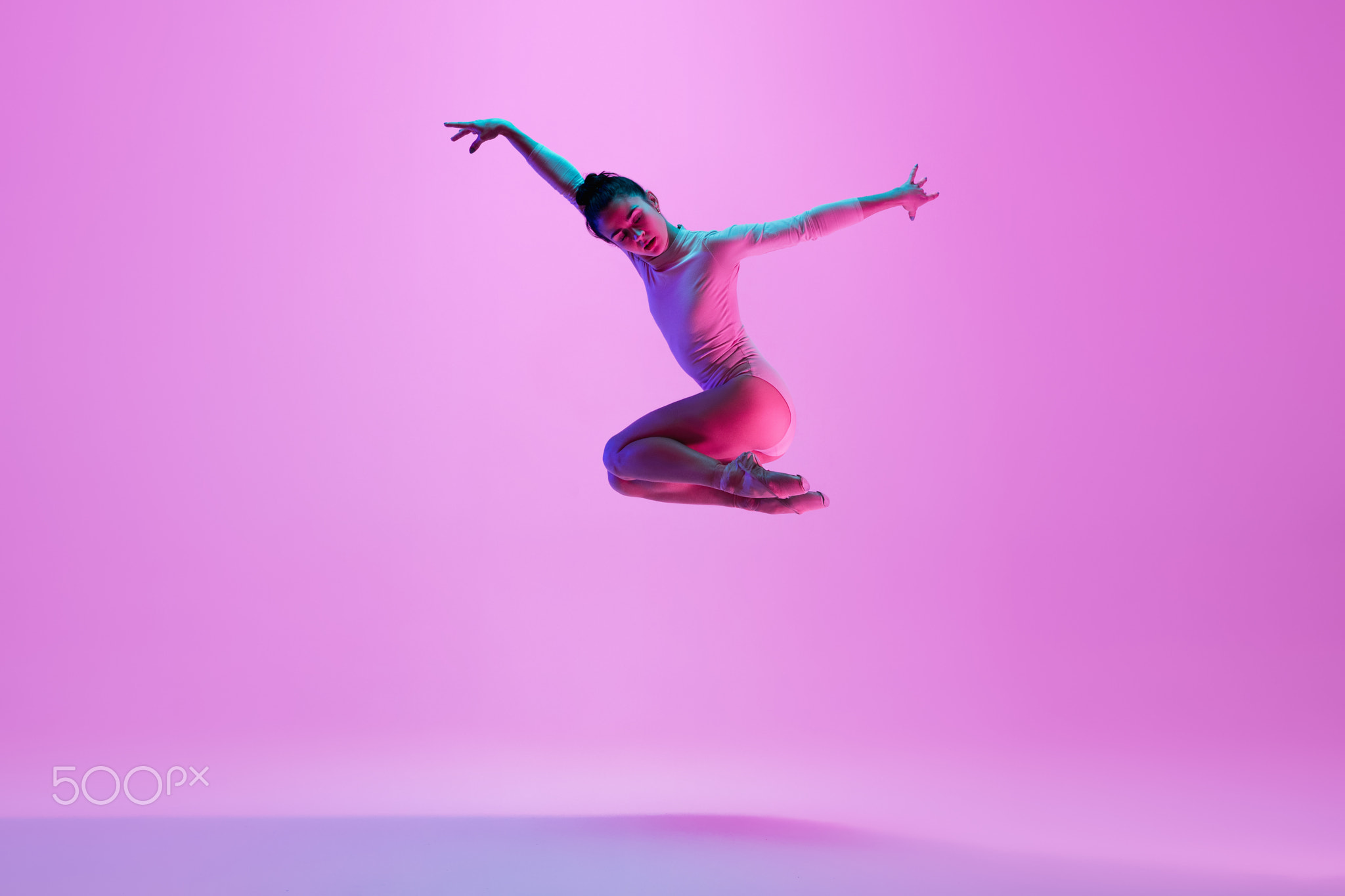 Young and graceful ballet dancer isolated on pink studio background in