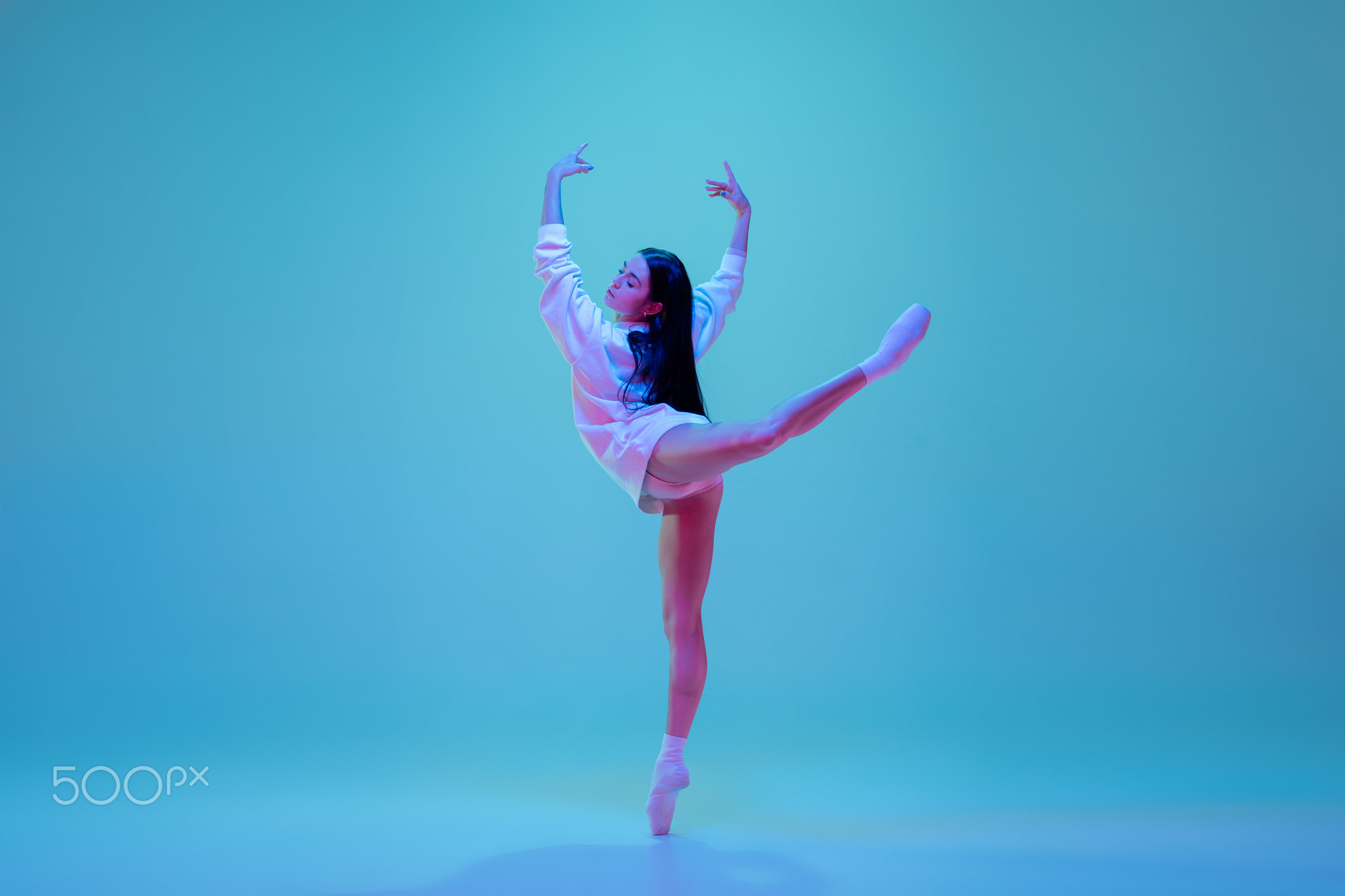Young and graceful ballet dancer isolated on blue studio background in