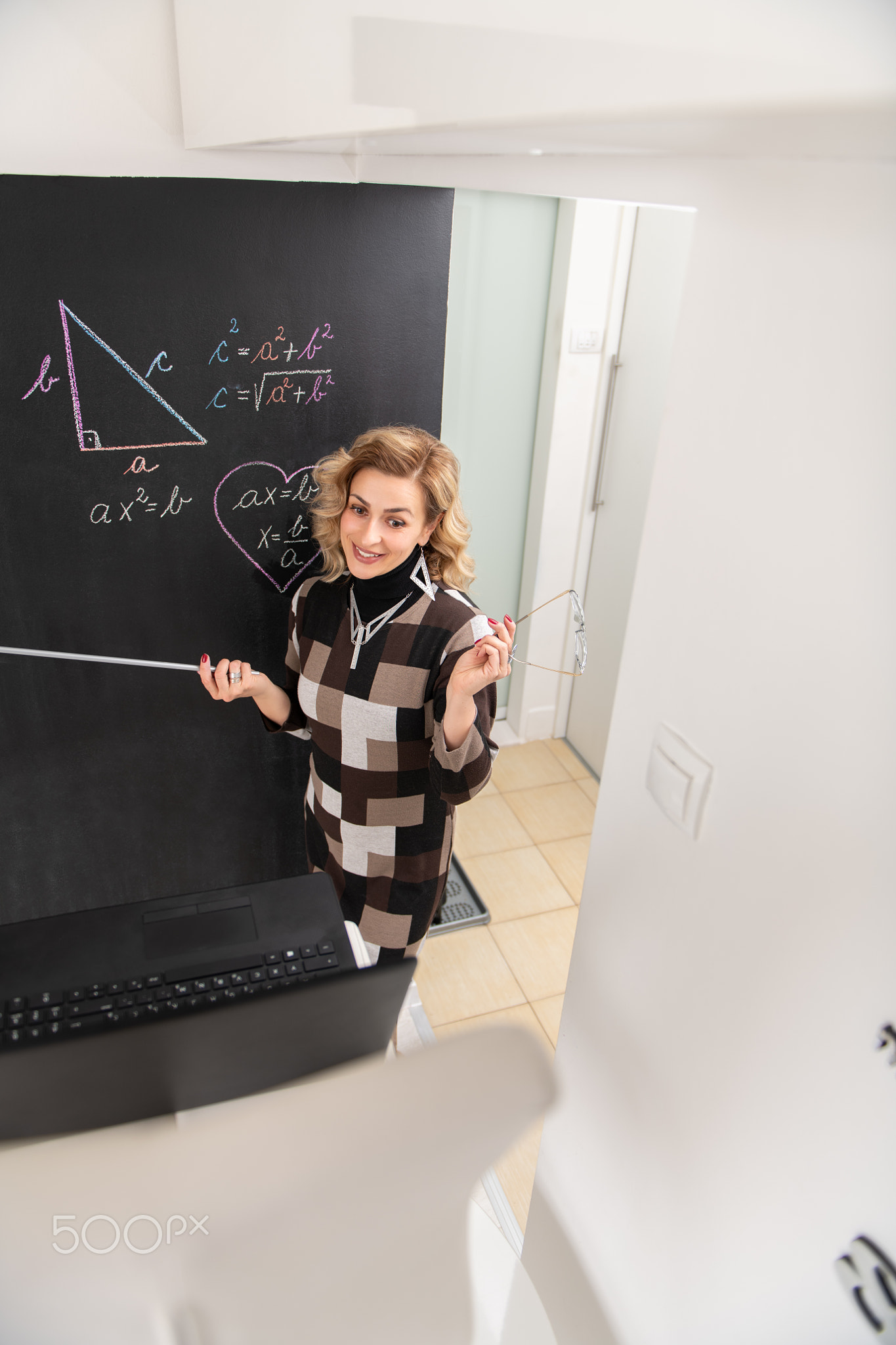 Young female math teacher explaining geometry on the black wall