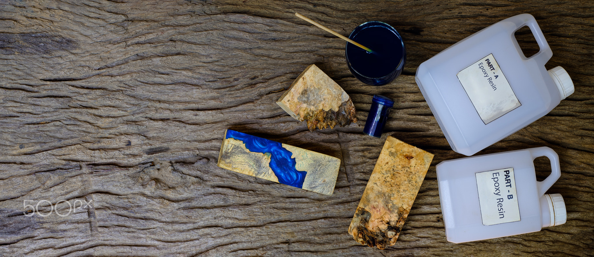 Mixing color blue epoxy resin in a glass cup for casting burl wood