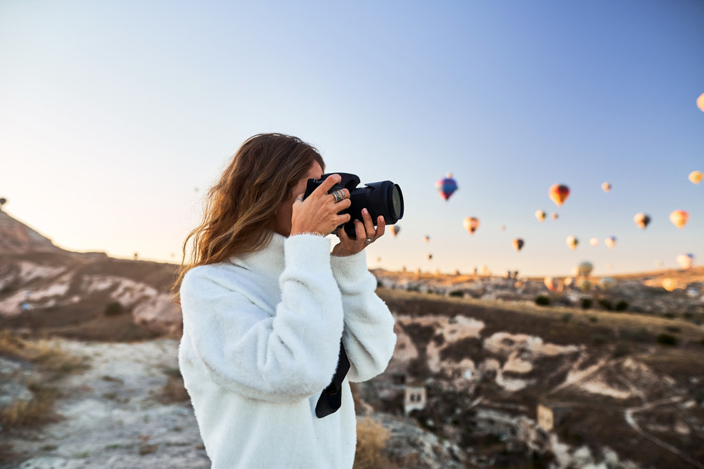 Une photographe touristique portant un pull blanc au sommet d'une montagne par Roma Black sur 500px.com