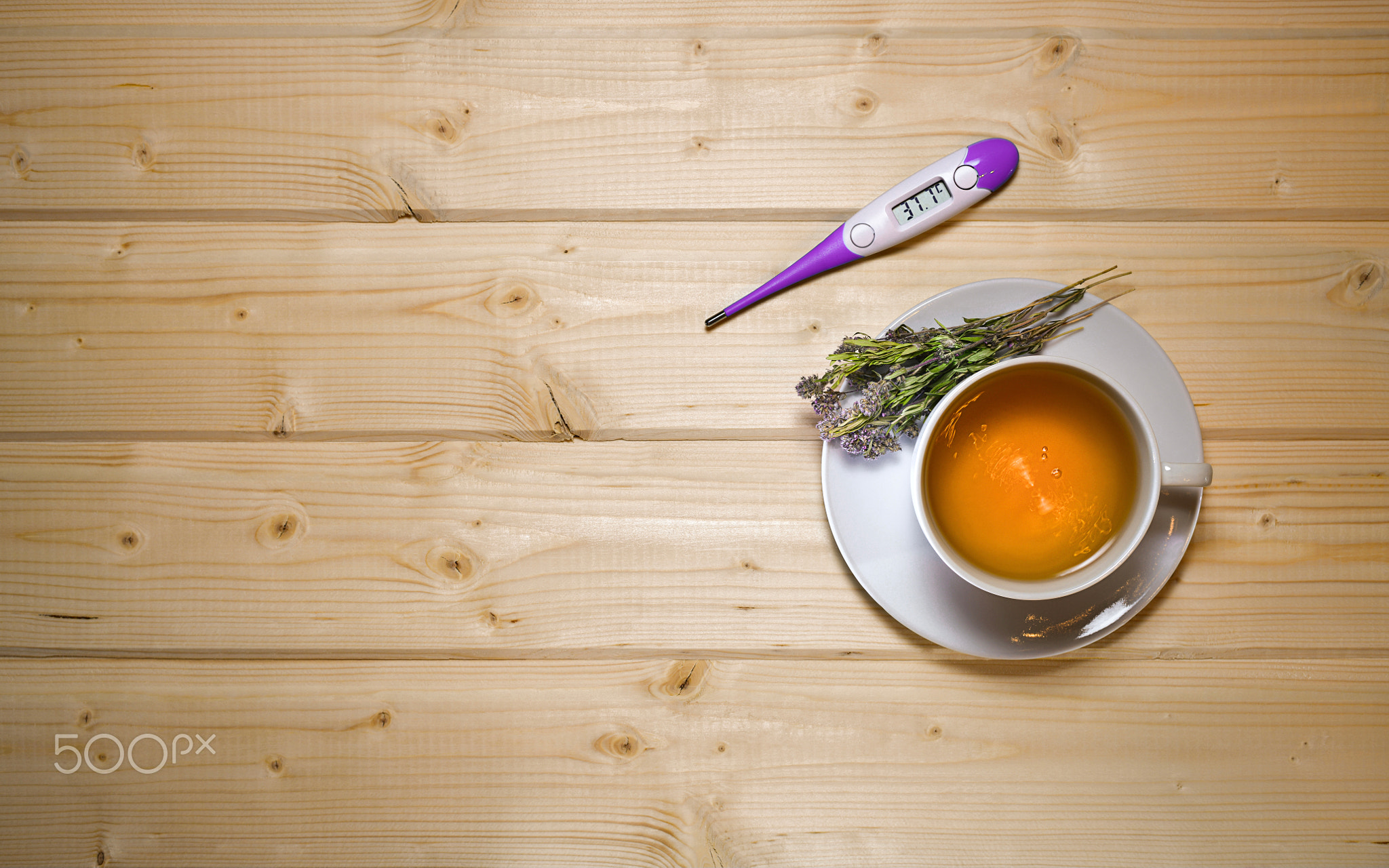 A cup of herbal tea with waves. With a thermometer and flowers on a