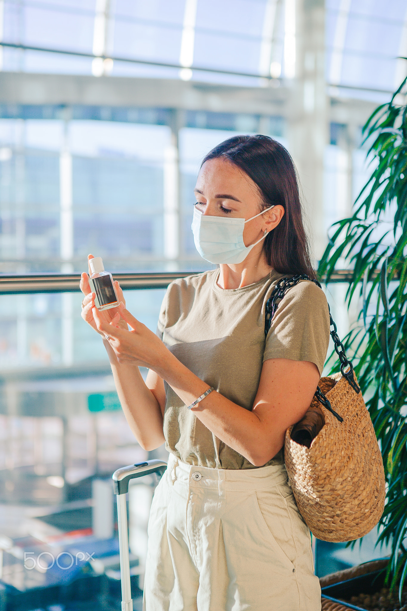 Young tourist woman in medical mask with baggage in airport