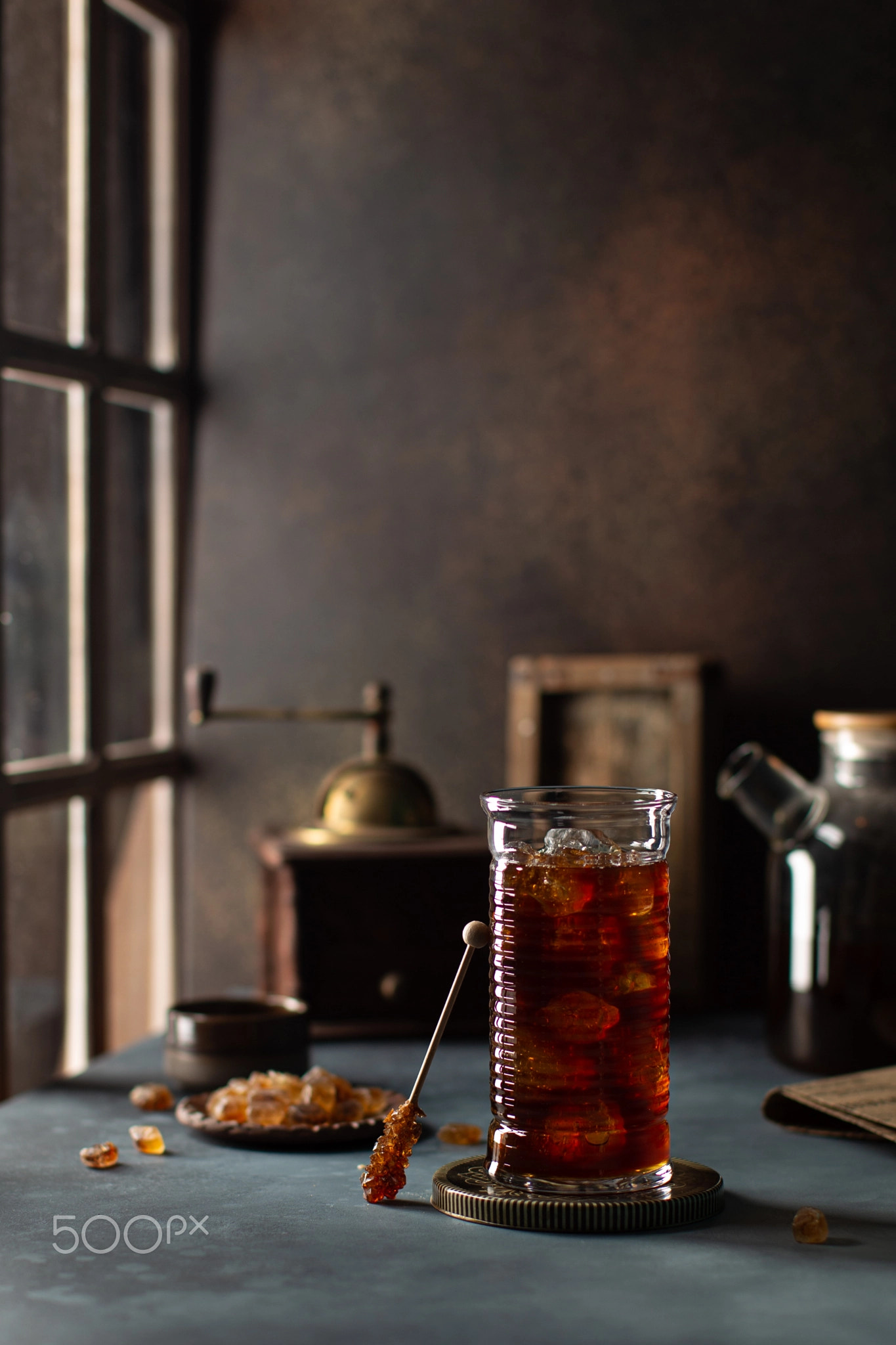 Glass of iced coffee on the table near the wooden window with vintage