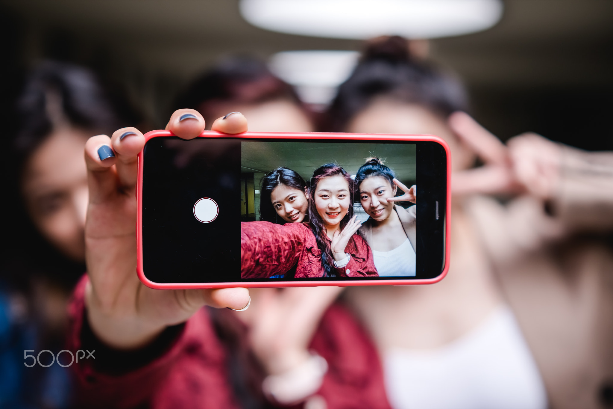Group of female friends taking a selfie together with a mobile phone