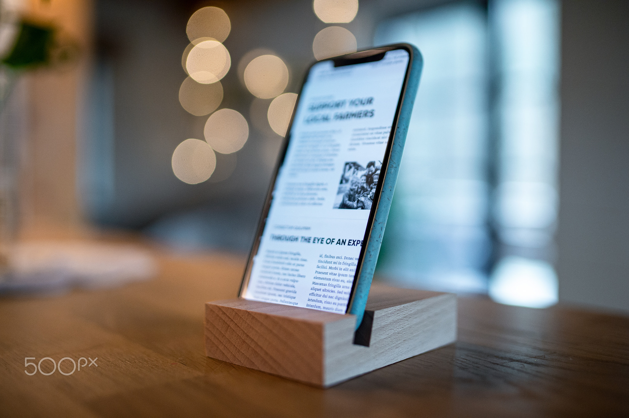 Smartphone in wooden stand holder on table indoors at home or on