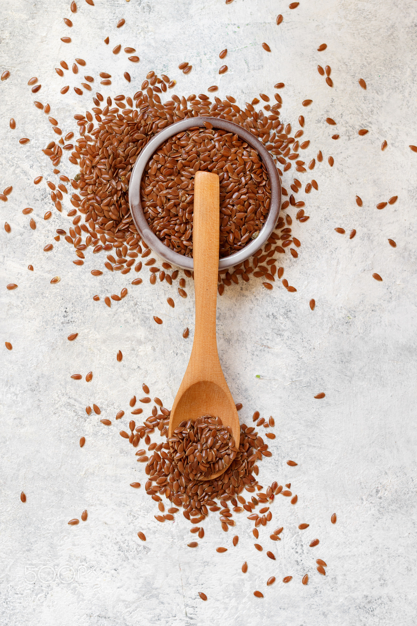 Raw Flax seeds in a bowl with a wooden spoon
