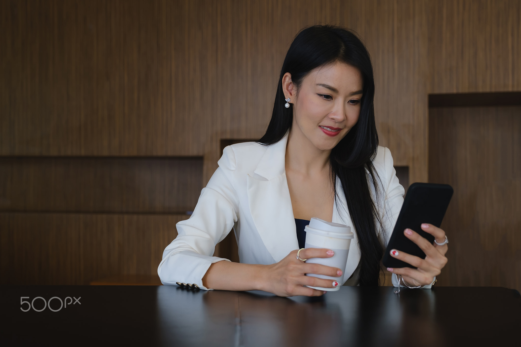 Businesswoman using mobile phone with smile and sitting at her office