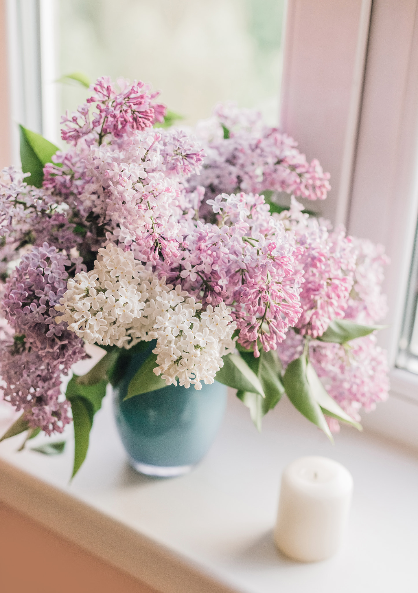 Bouquet of lilacs in a vase,cup of coffee and books on the windowsill.