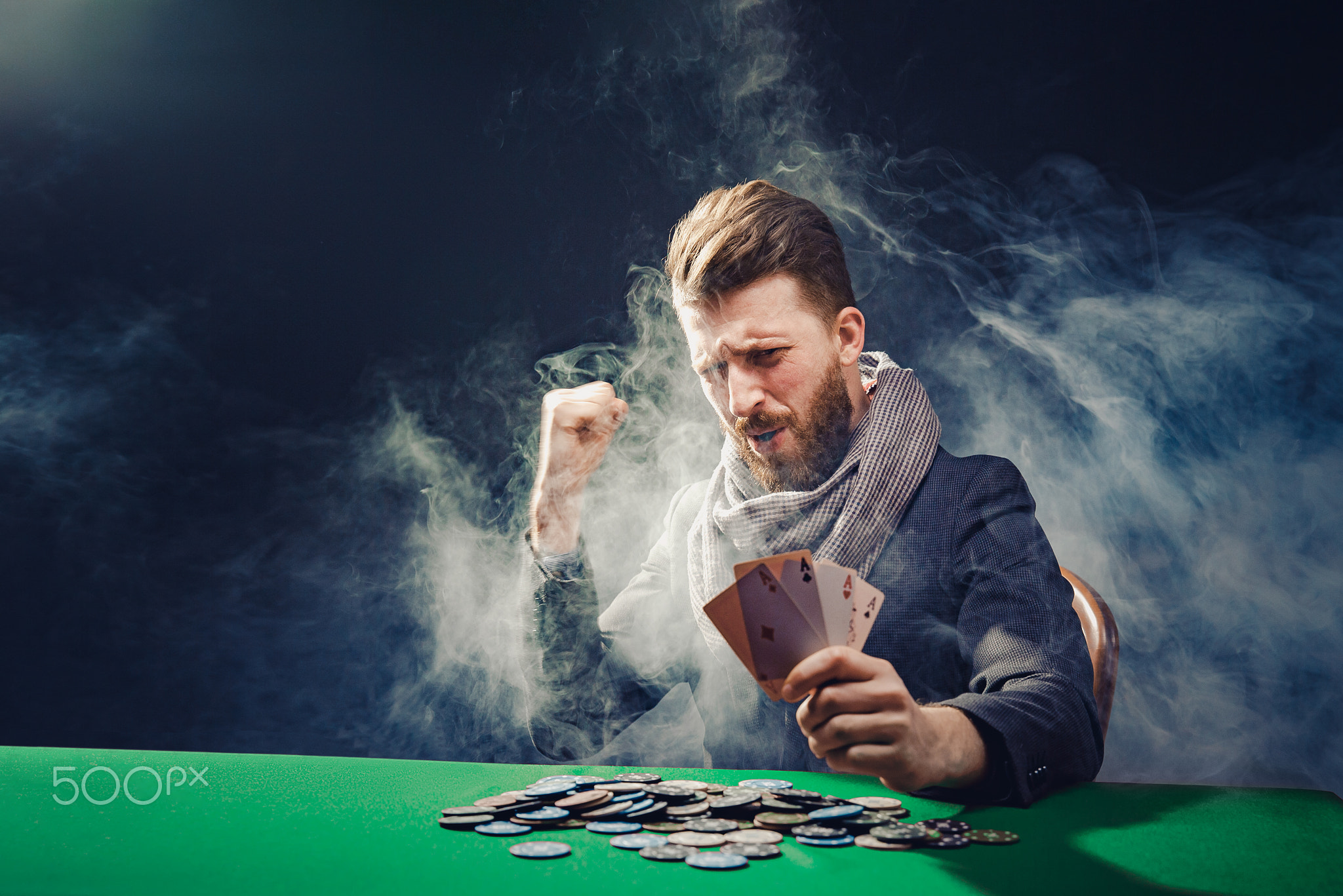 Happy poker player winning and holding a pair of aces