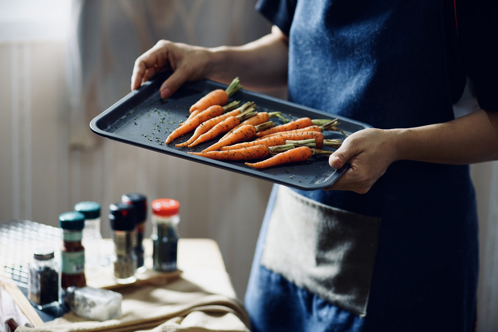 A woman holding a baking tray of baby carrot by Studio OMG on 500px.com