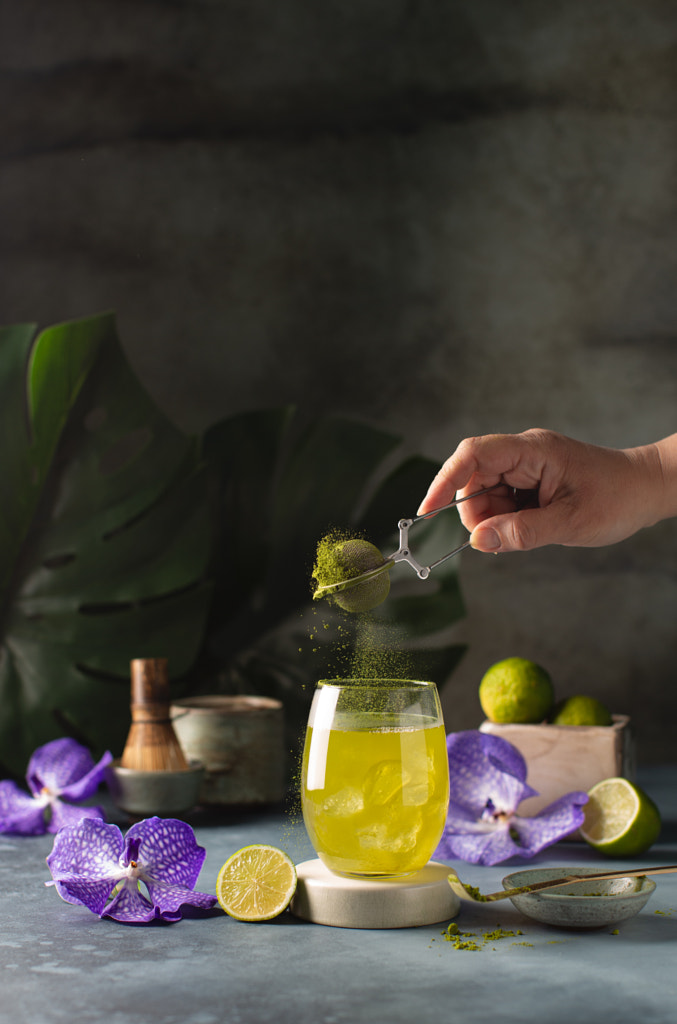 Hand giet theepoeder in glas met ijsgroene Matcha, verse limoenen, met door Olga op 500px.com