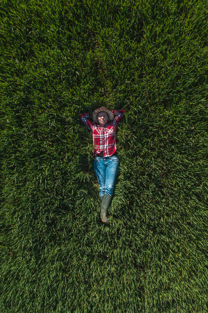 Aerial view of female farmer laying in green wheat field by Igor Stevanovic on 500px.com