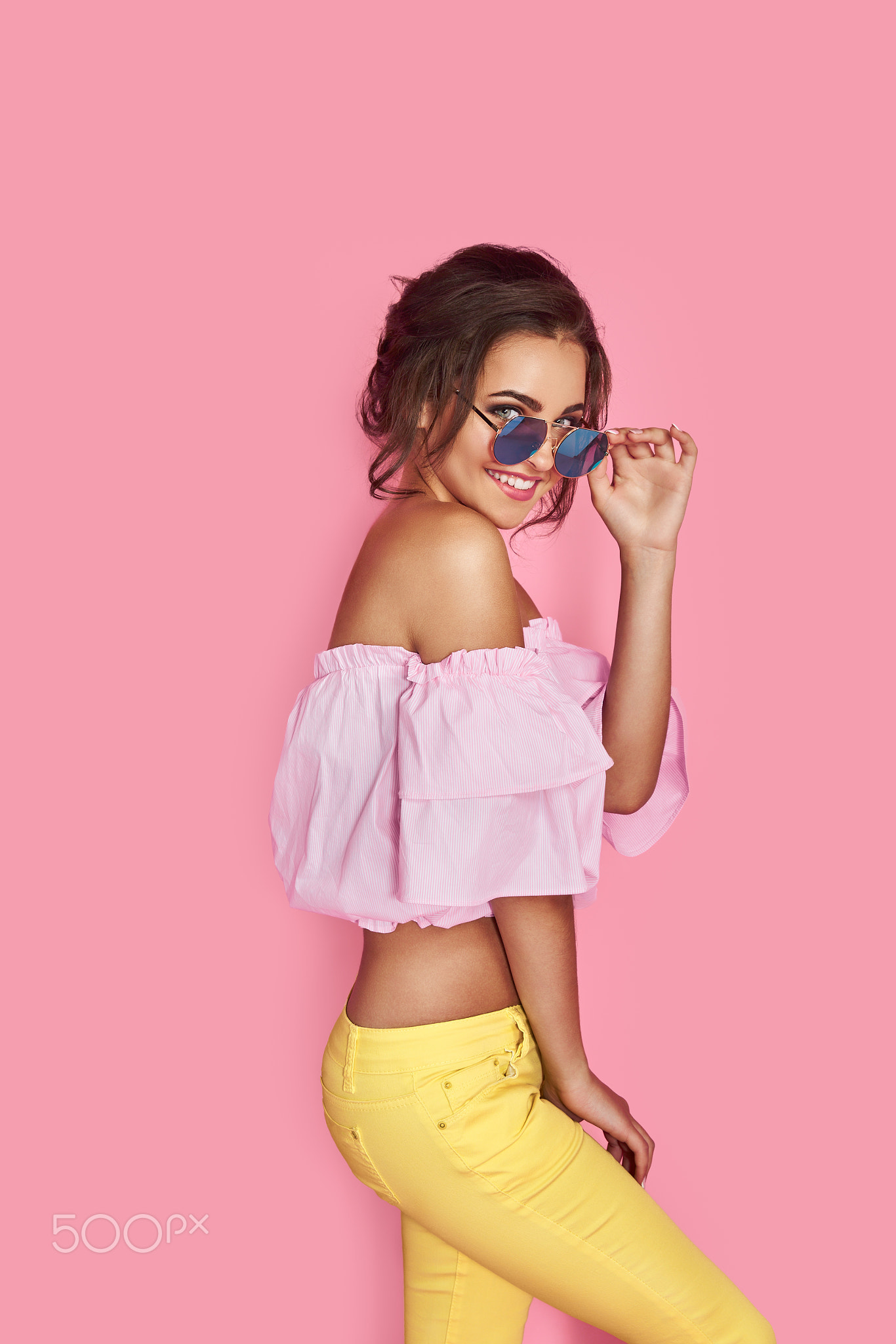 Beautiful girl in yellow jeans and pink shirt, with hands up wearing