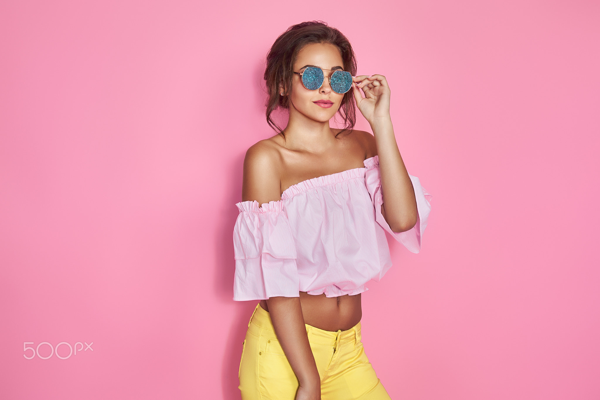 Beautiful girl in yellow jeans and pink shirt, with hands up wearing