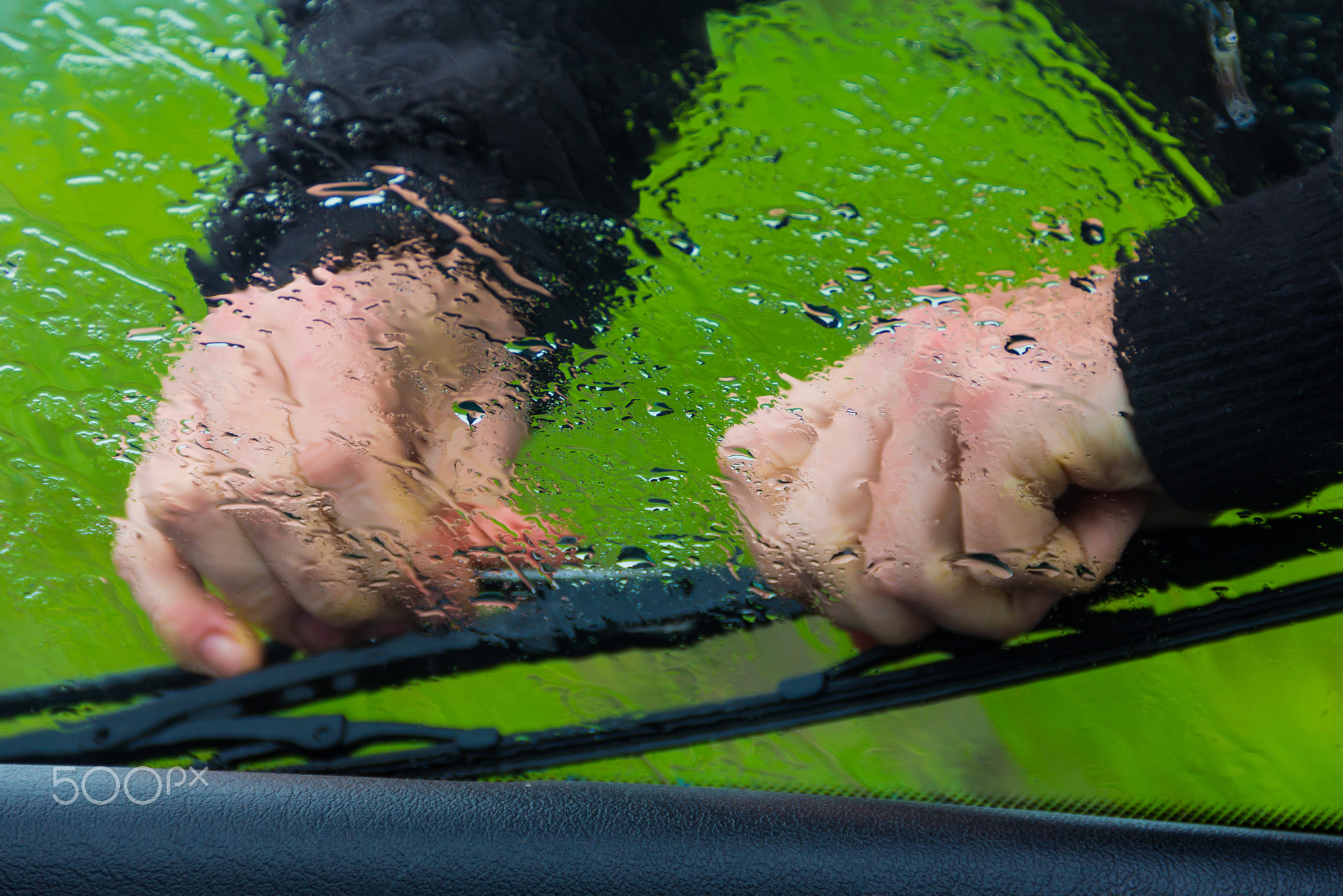 the man in the rain repairs a window wiper by car