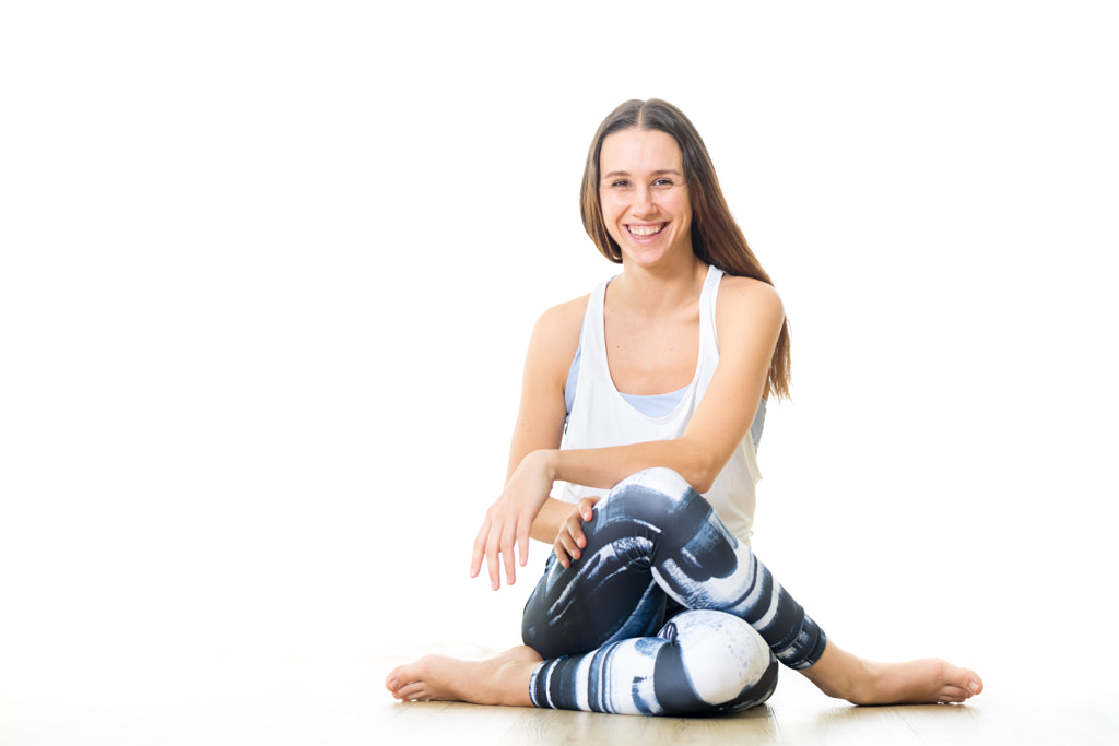Young sporty female yoga instructor in bright white yoga studio