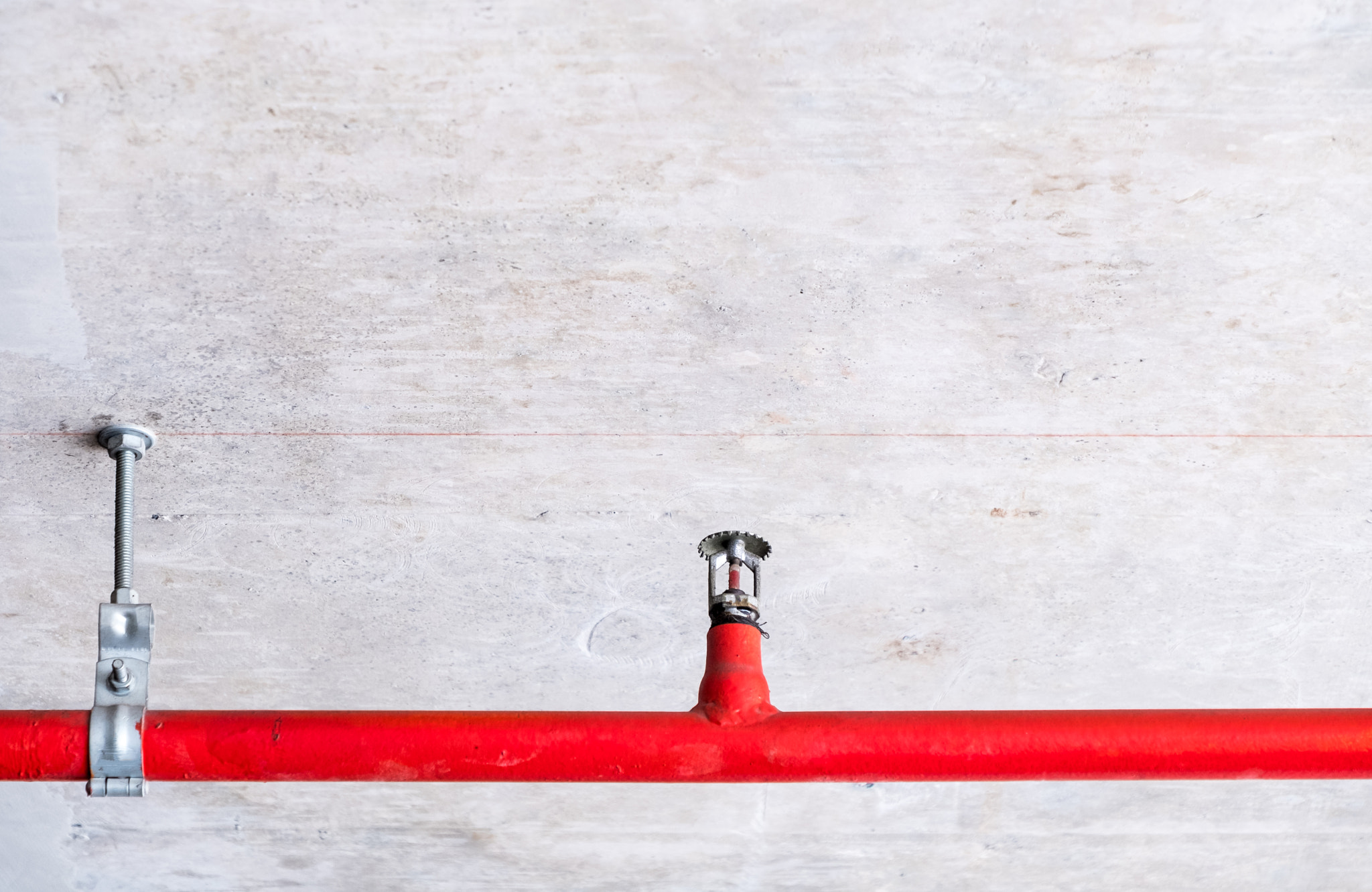 Automatic fire sprinkler on the red metal pipe.