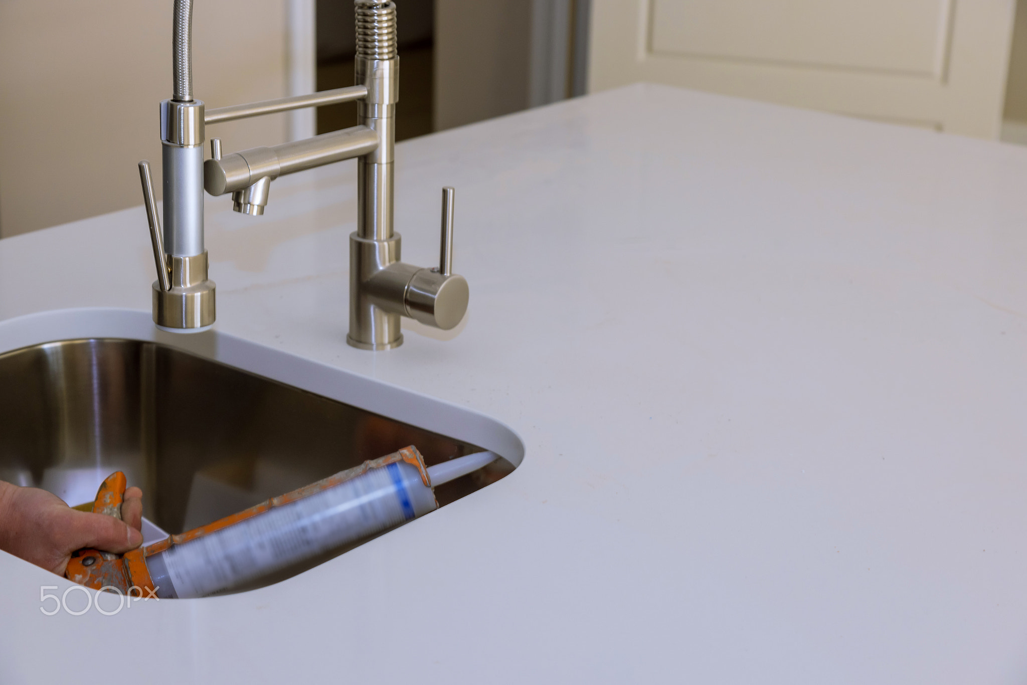 Worker installing granite sink in kitchen silicone sealant on granite