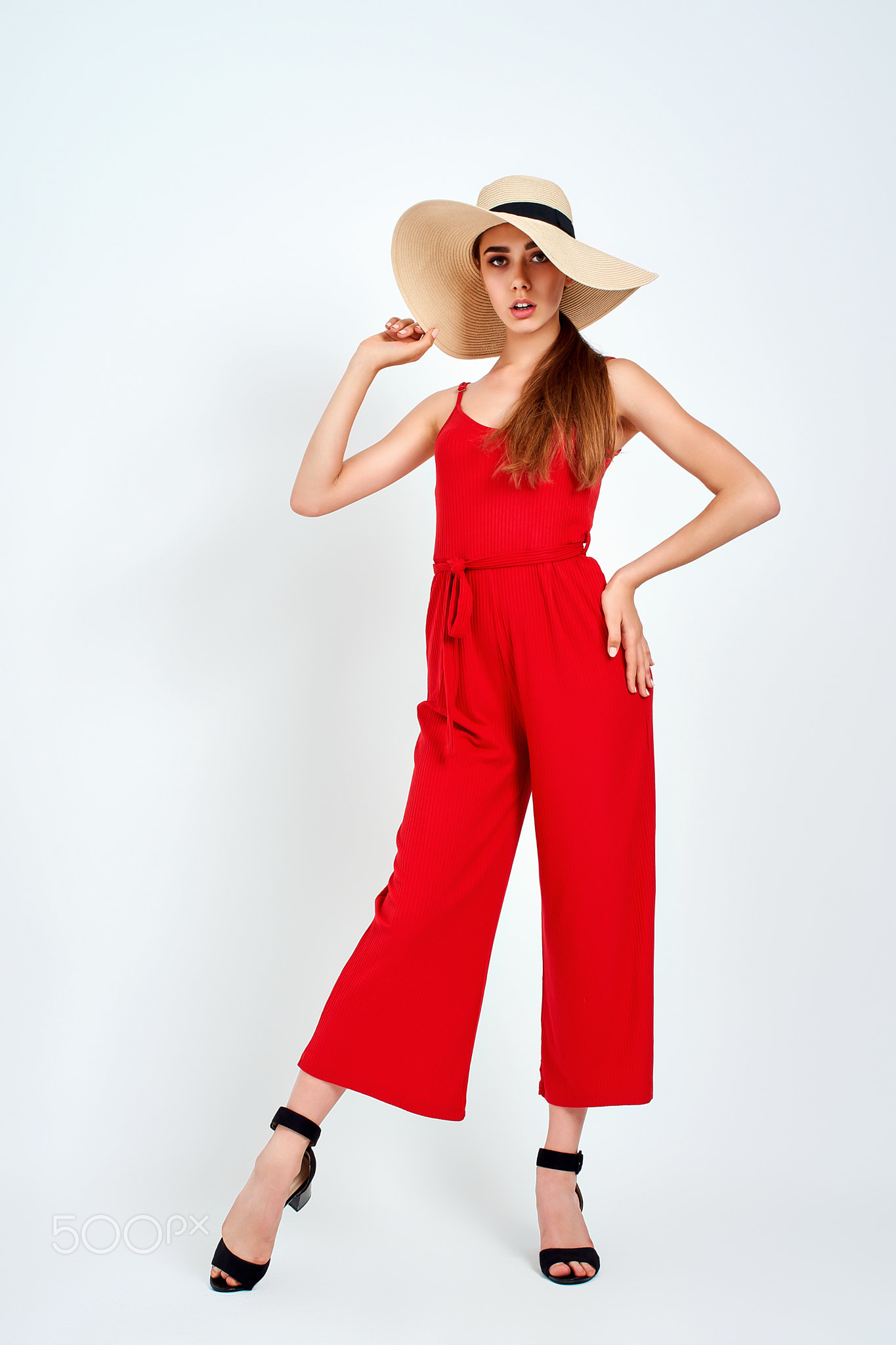 Beautiful girl in sun hat standing on white background in studio in