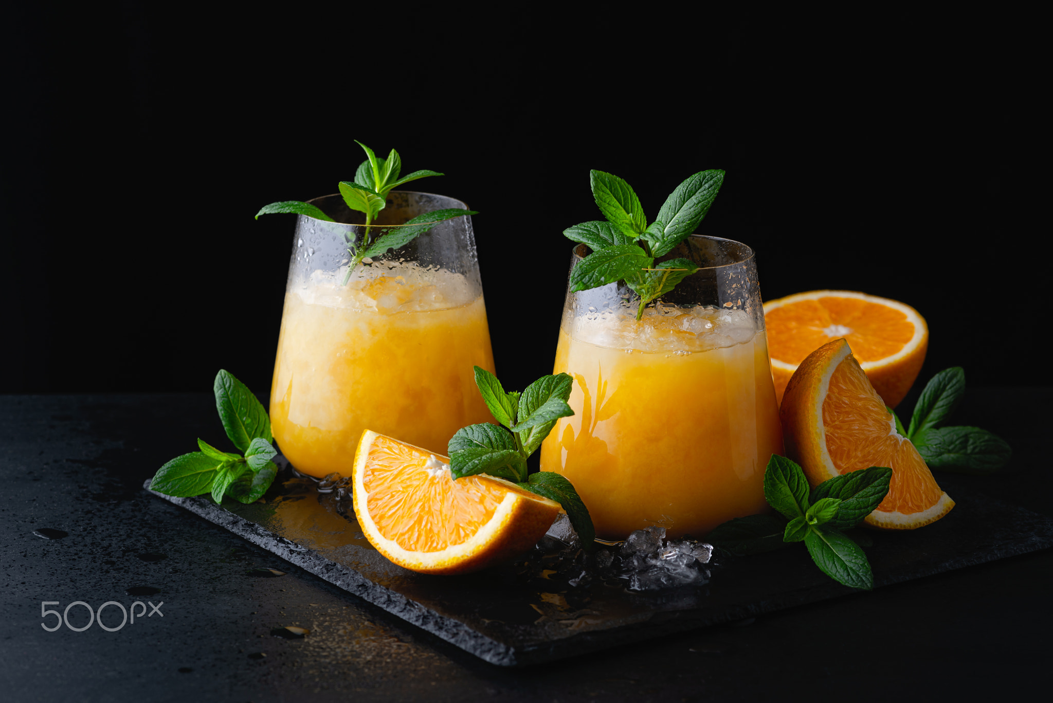 Cold summer orange lemonade with mint and ice in a glass.