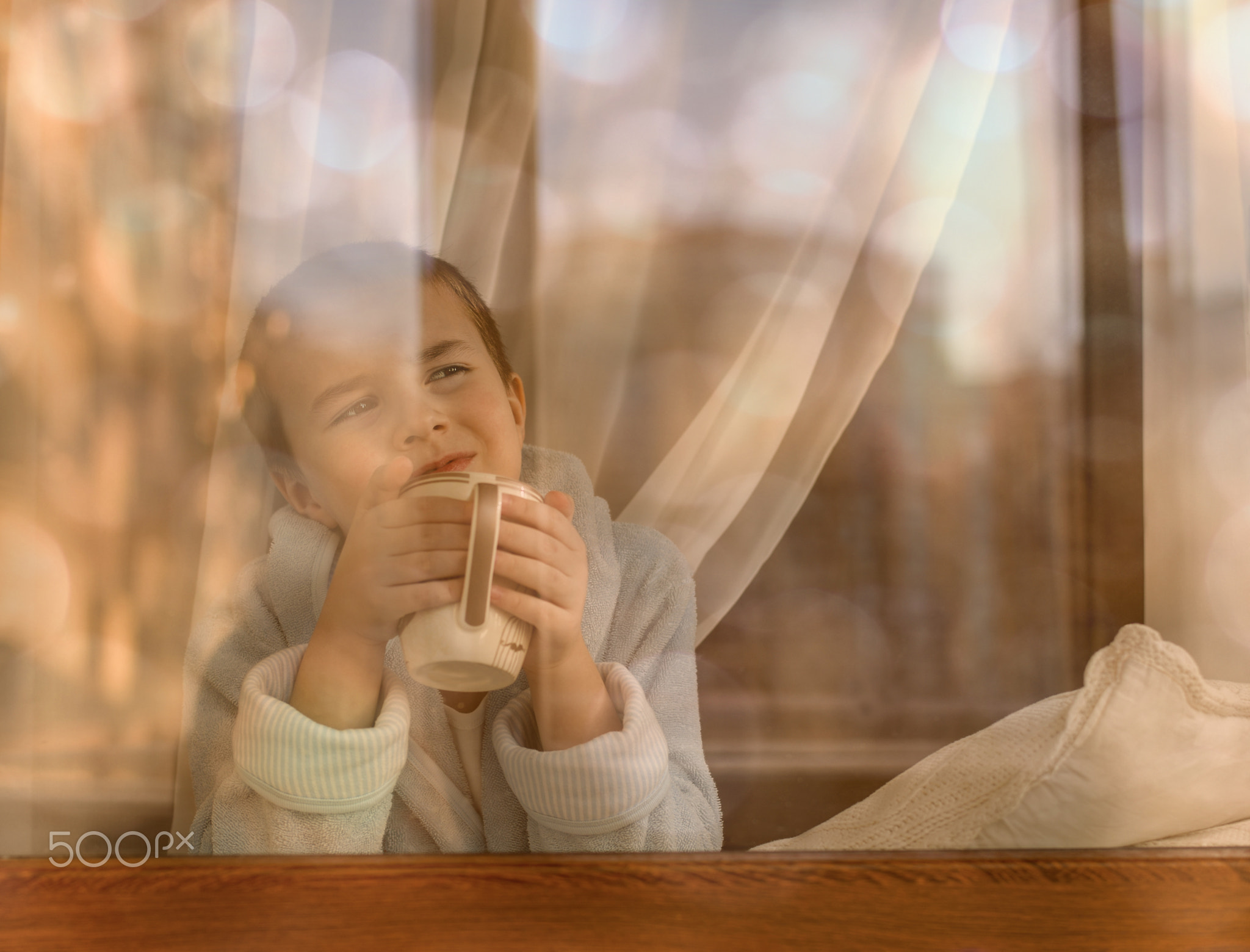 The boy looks out the window and dreams.