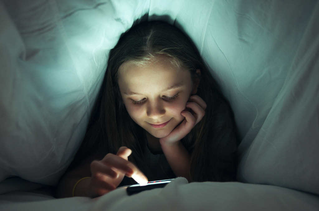 Young girl using a phone in bed by George Mdivanian on 500px.com
