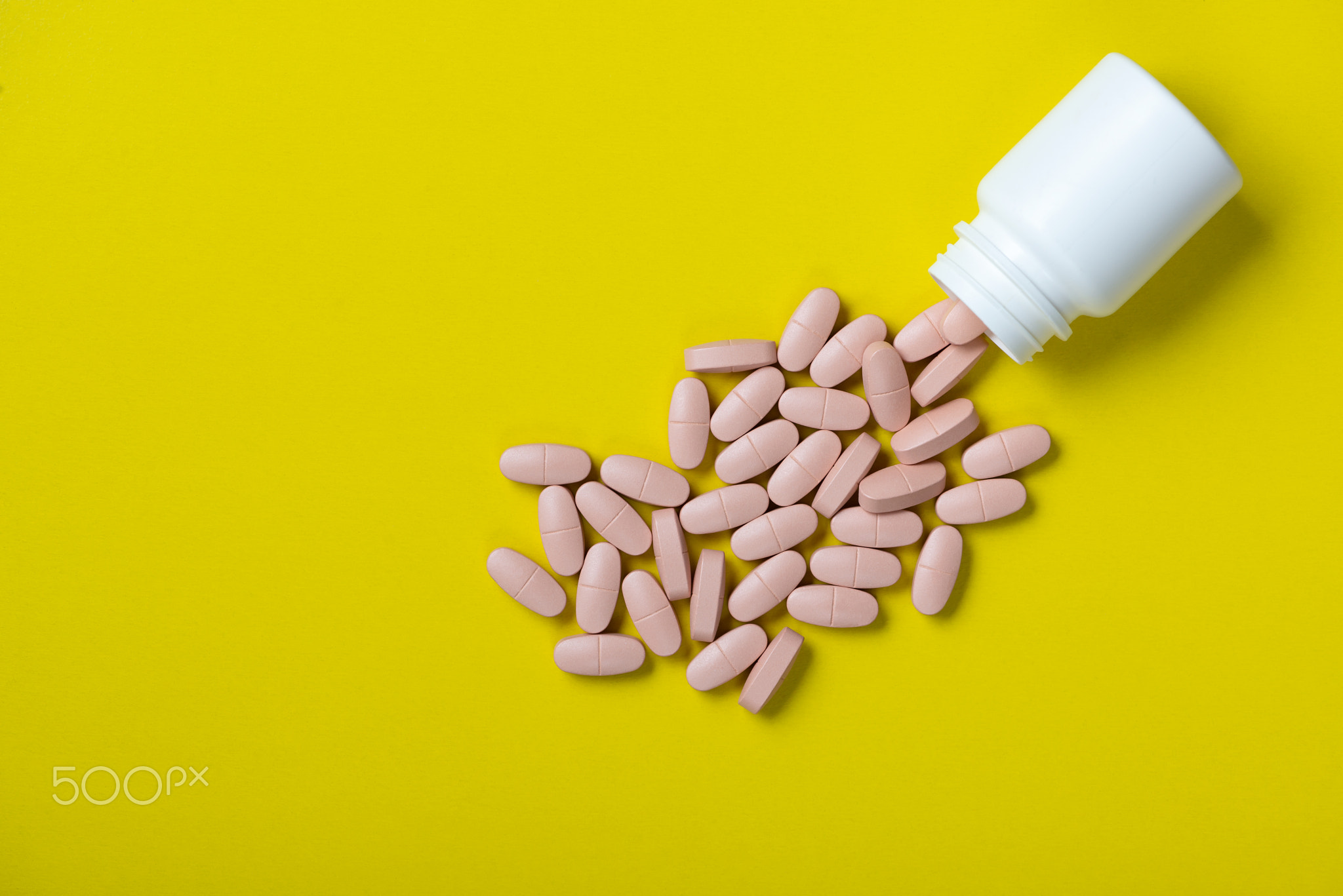 Pills with bottle isolated on yellow.