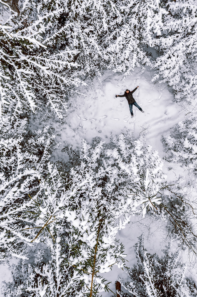 500px.com üzerinde Eugene Gurkov tarafından yukarıdan çekilen kar kış ormanda yatan mutlu adam