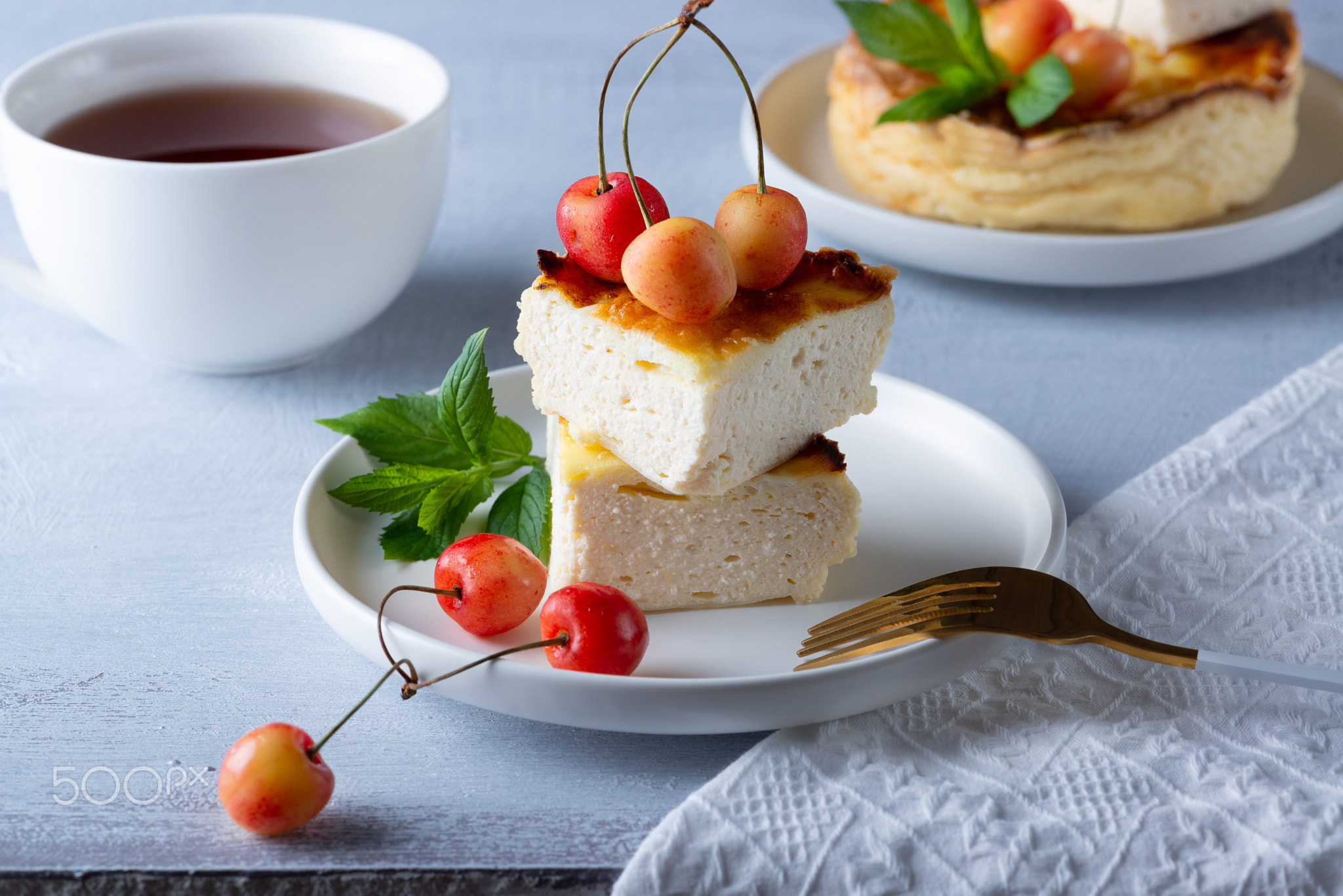 Cottage cheese casserole and sweet cherry on wooden light table.