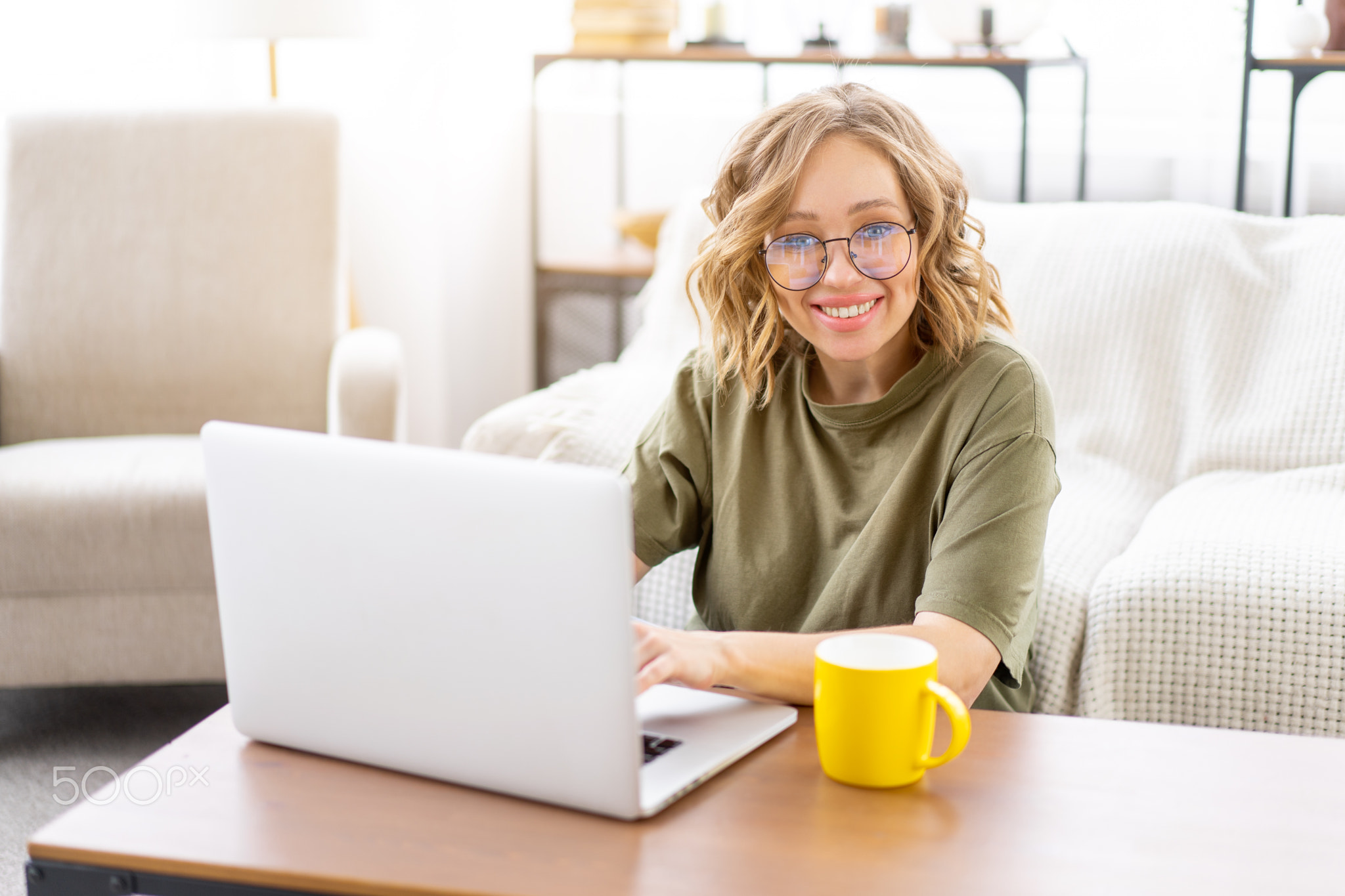 Woman glasses using laptop computer while sitting near sofa with big