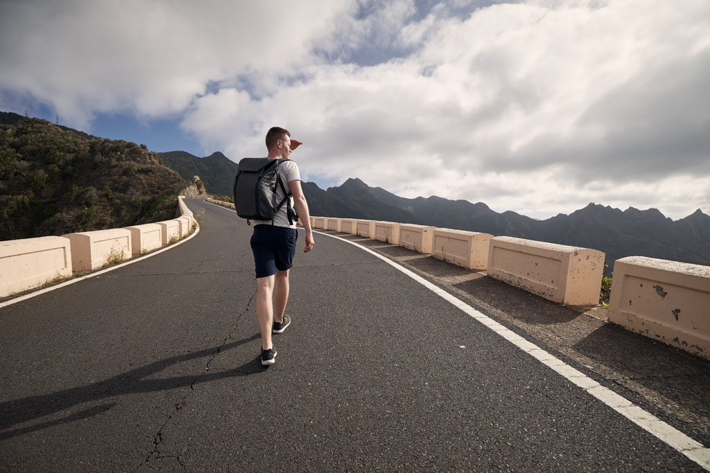 Rear view of man with backpack on mountain road by Jaromír Chalabala on 500px.com