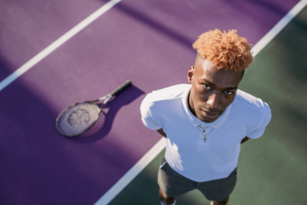 Young man standing on the court with tennis racquet on floor by Rushay Booysen  on 500px.com