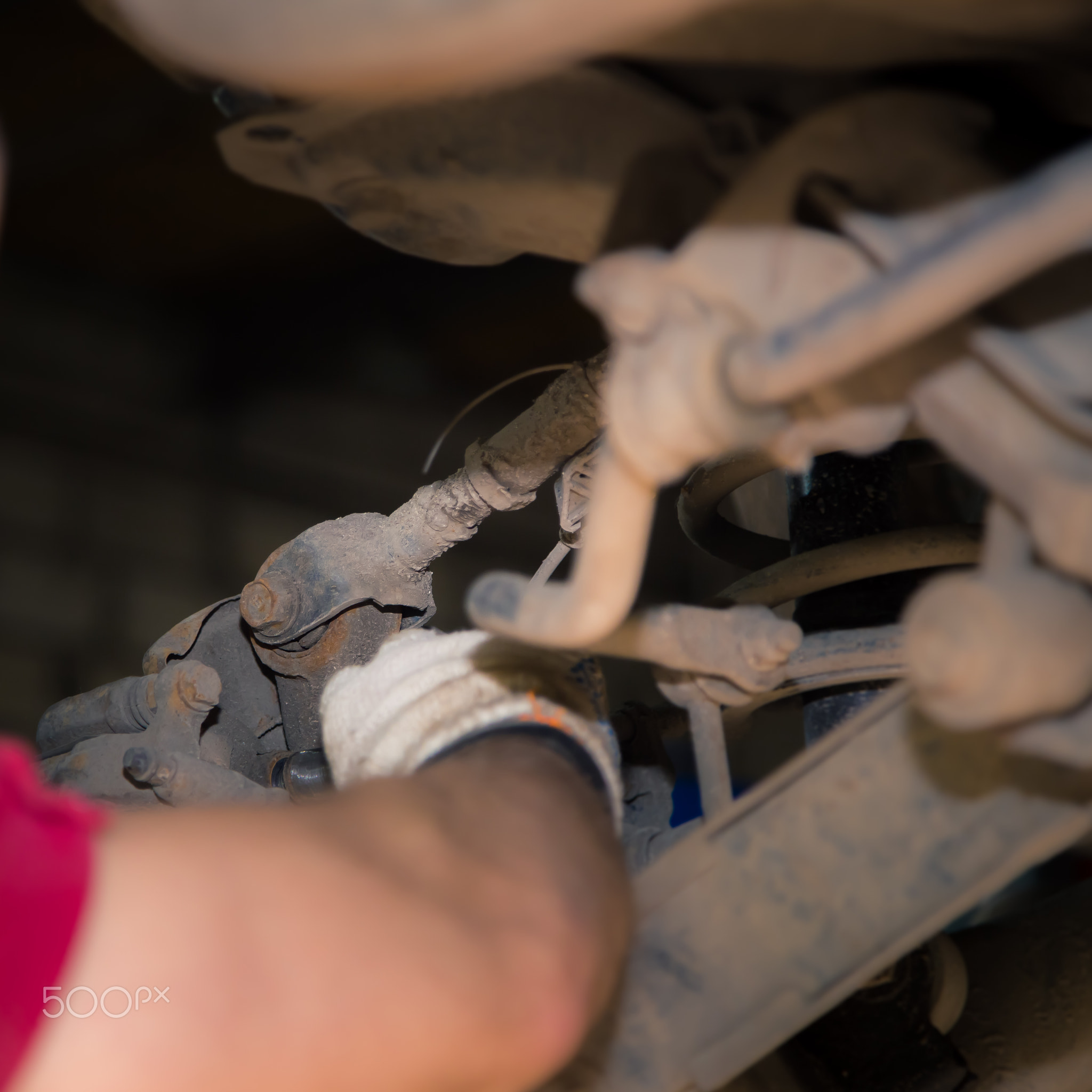 The man's hands unscrew the silent block in the chassis of the car.