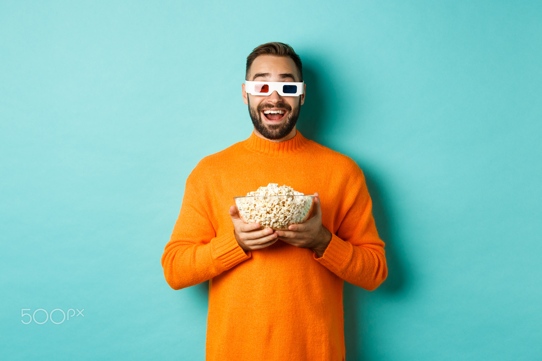 Happy guy watching movies in 3d glasses, eating popcorn and looking at