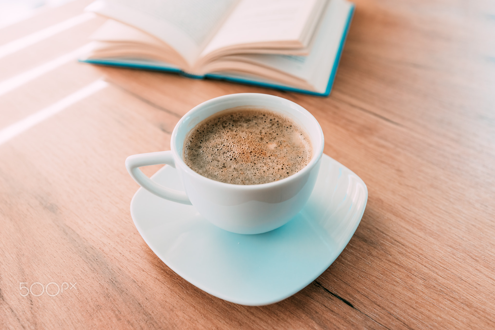 Coffee cup on the table, open book in background