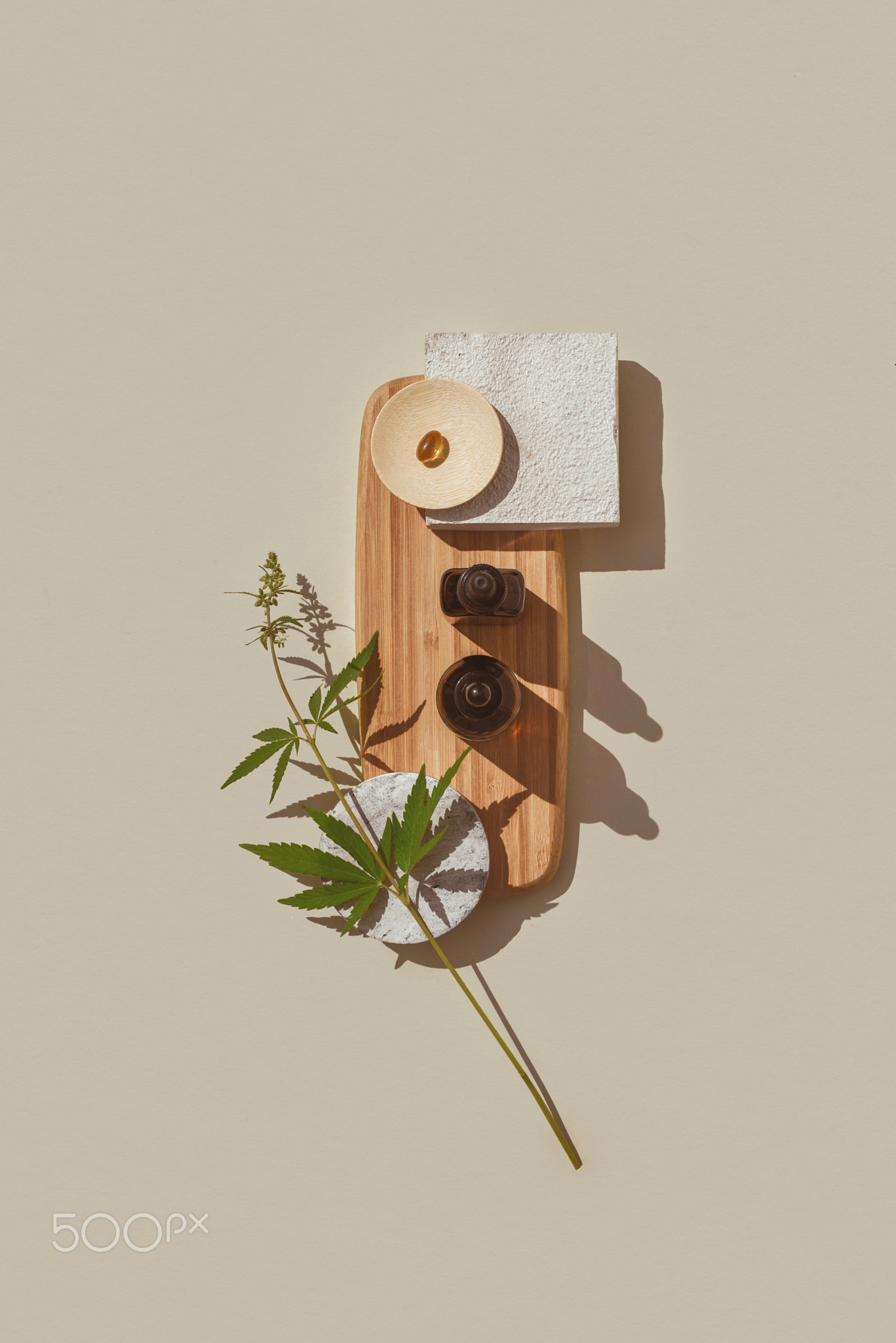 CBD oil in brown bottle, cannabis branch, capsules on wooden podium