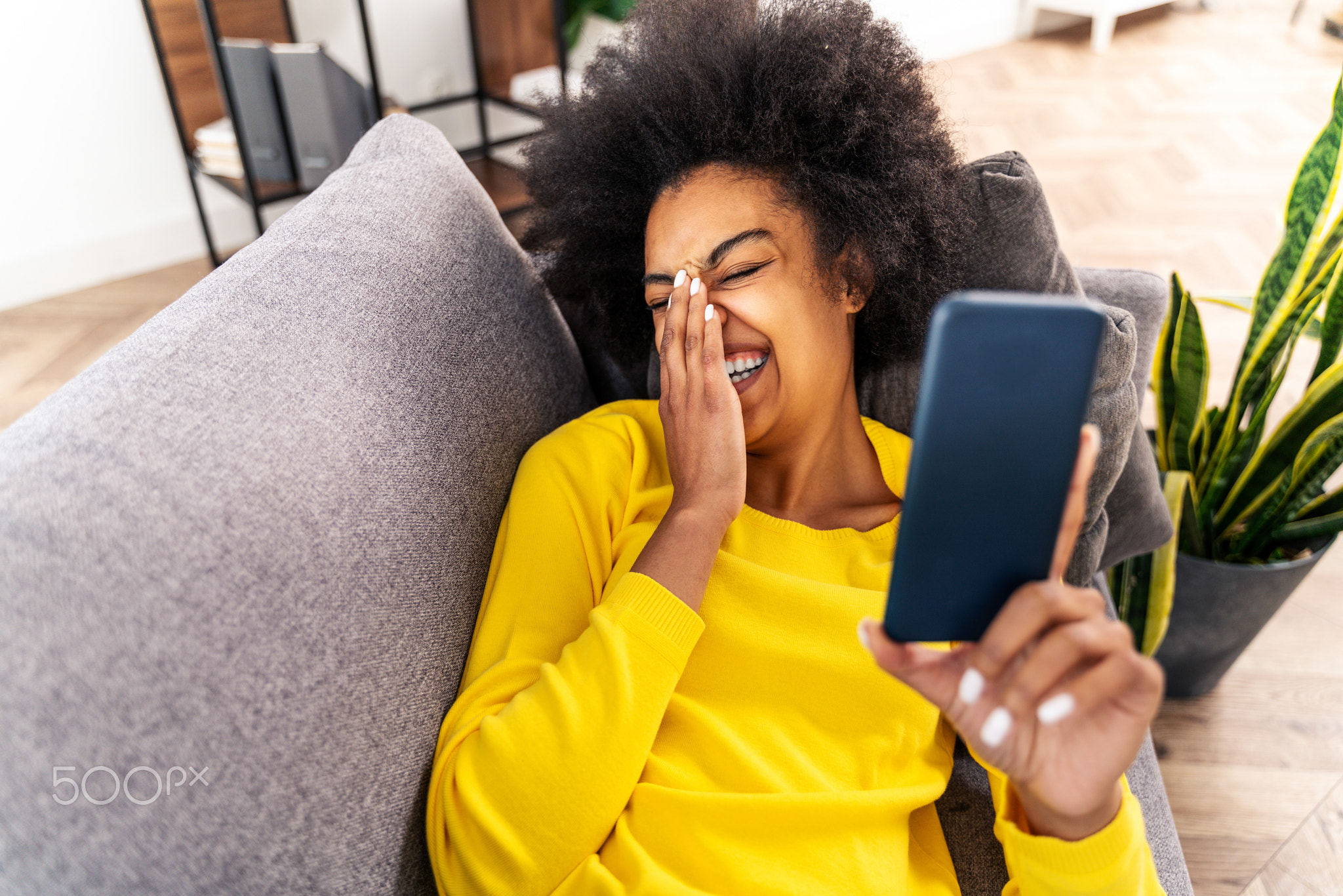 Afro american woman at home holding her smartphone