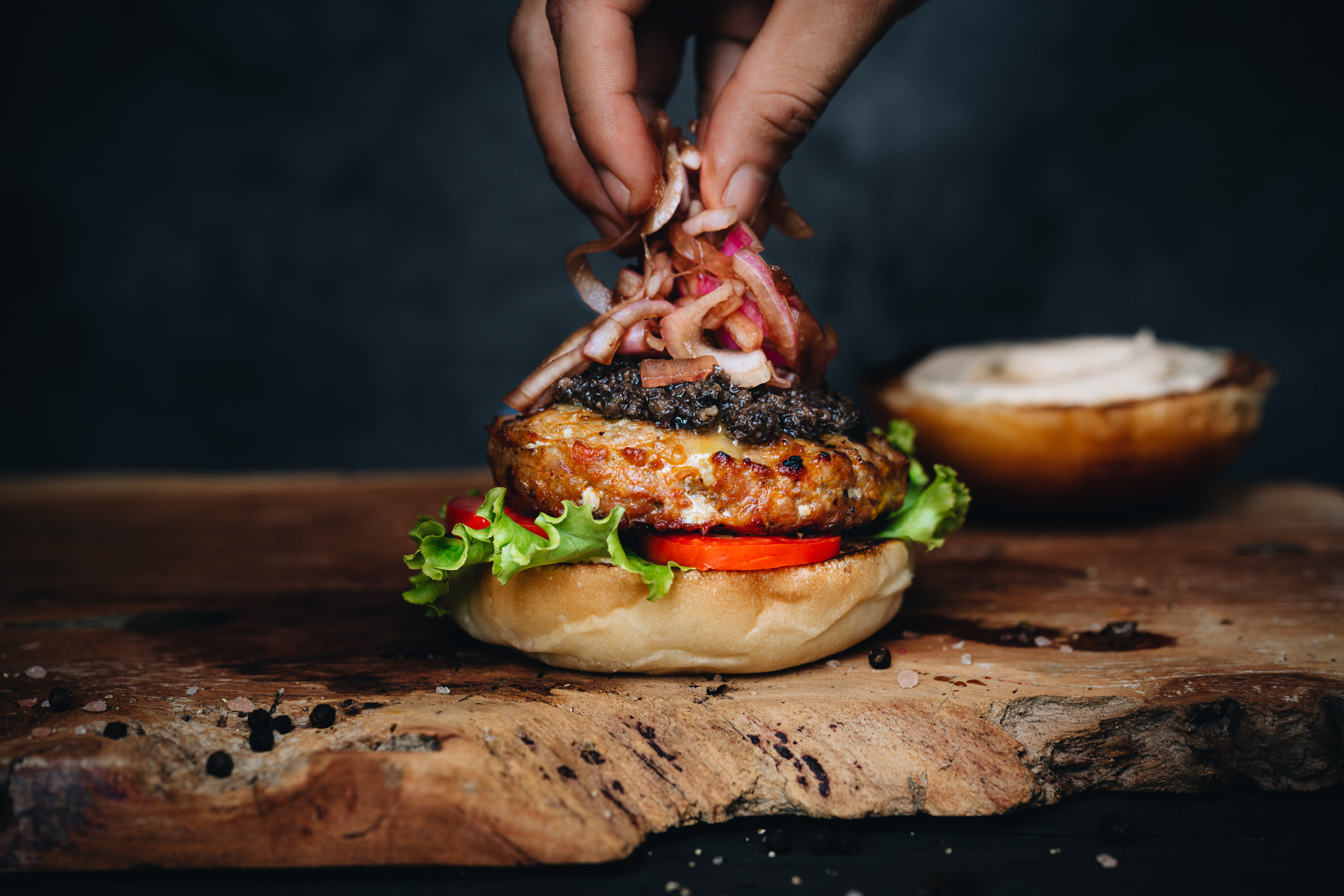 Burger with marinated onion and truffle paste on wooden board
