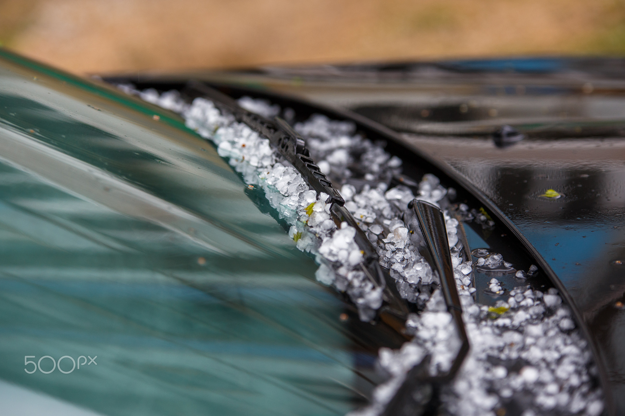 small hail ice balls on black car hood after heavy summer storm