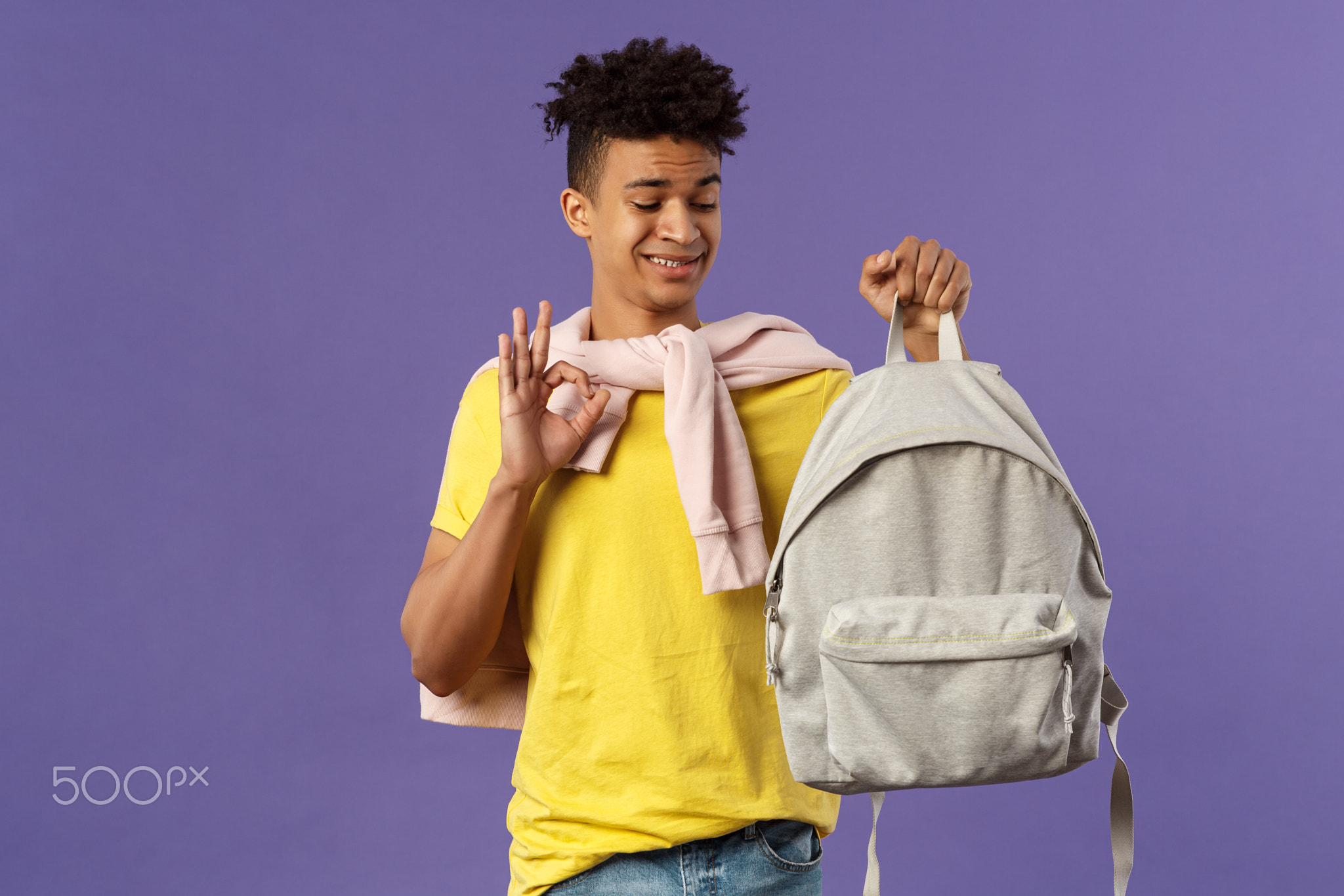 Portrait of young awkward guy, student receive gift new backpack from