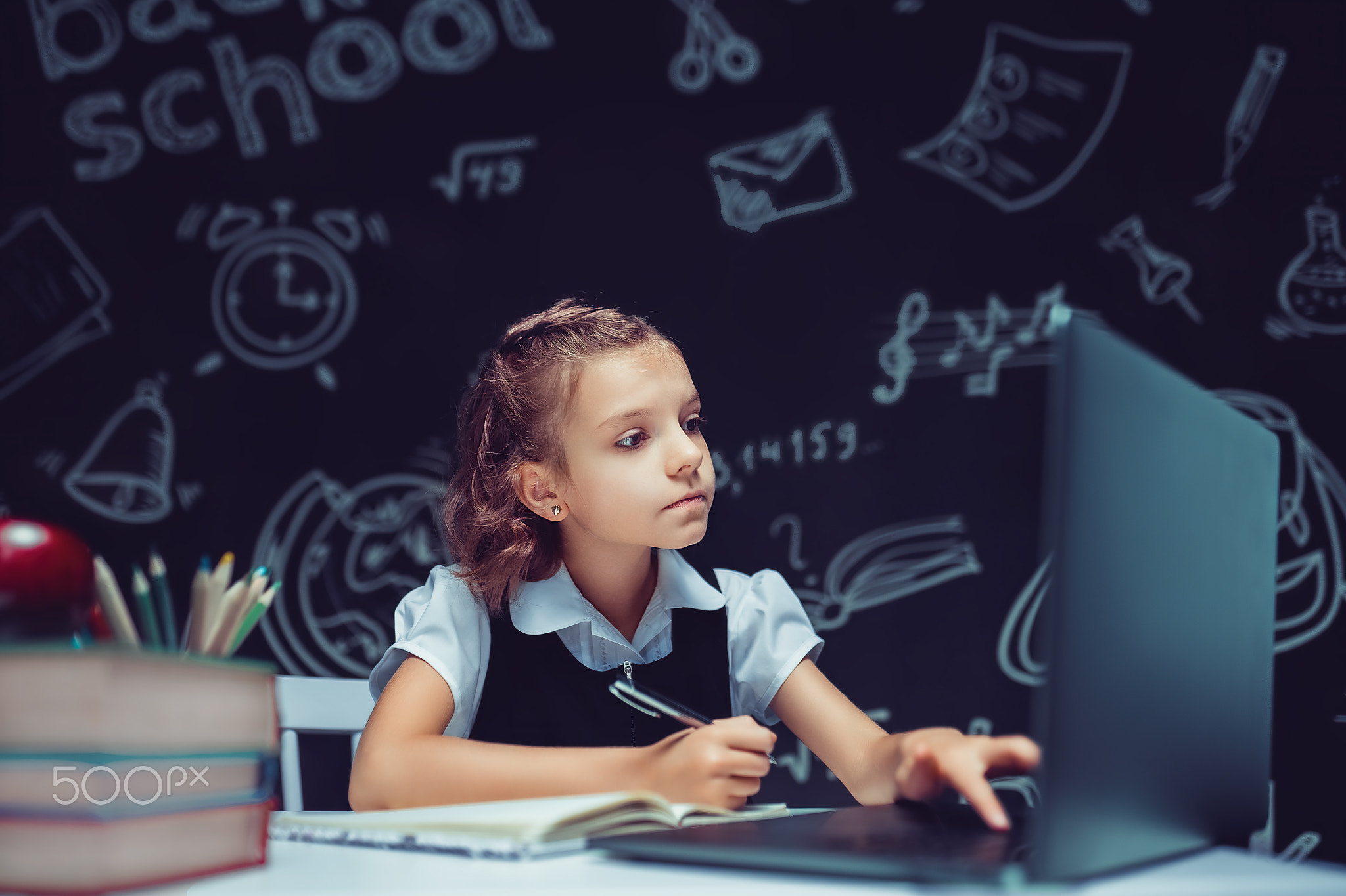 Happy teen school student studying with laptop books doing online