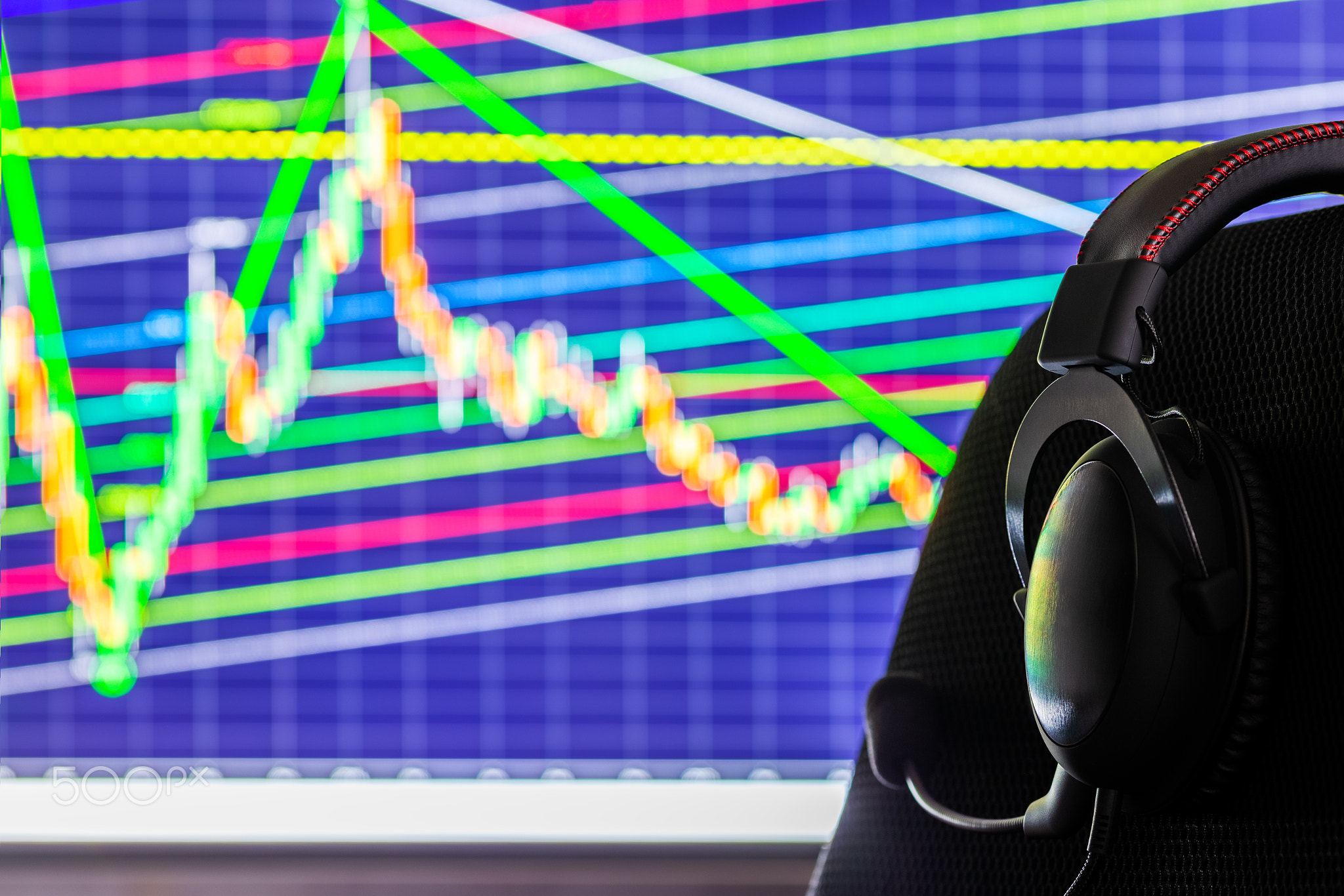 black headset on chair over monitor with trading chart in background -