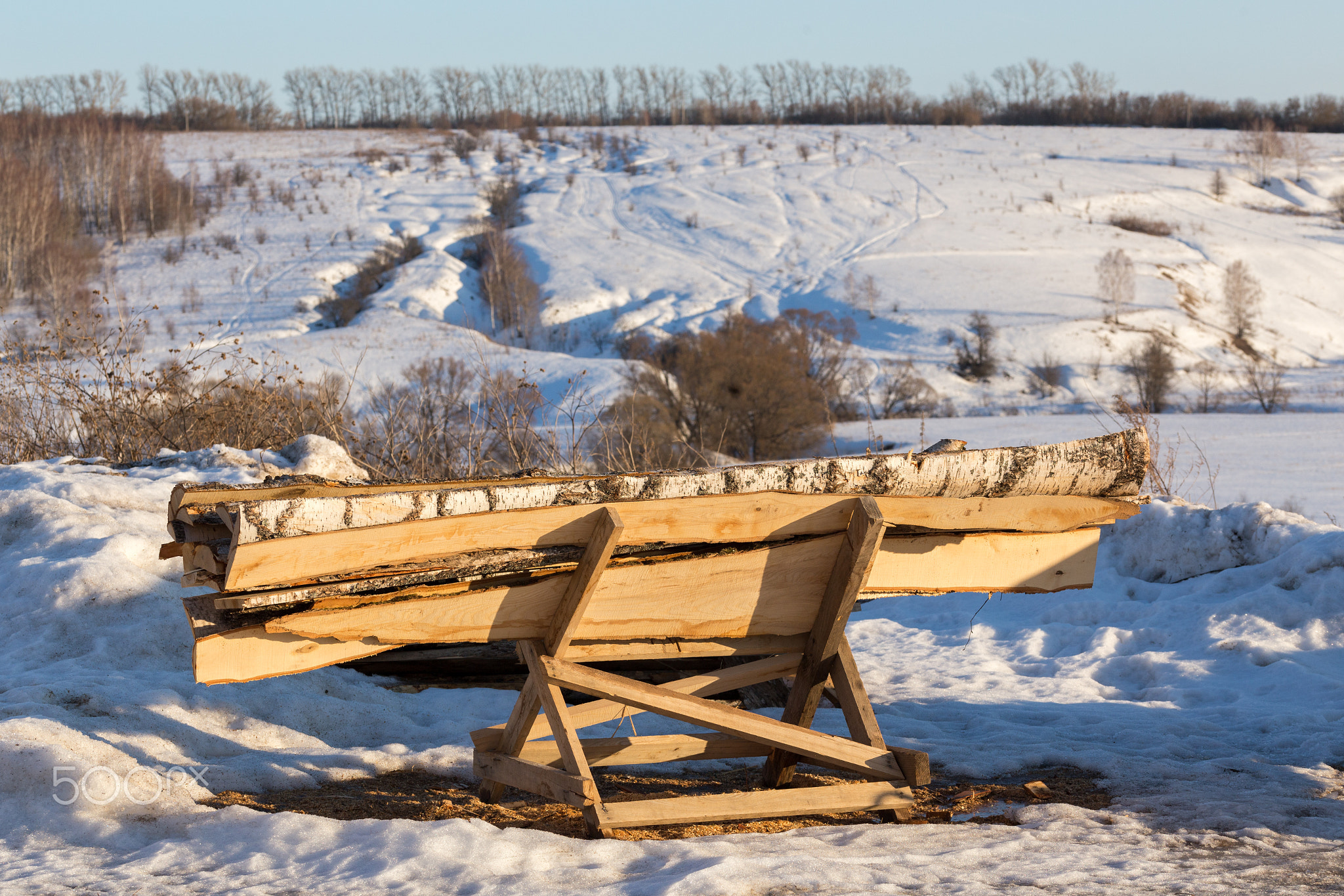 firewood lumber leftovers on trestle at winter evening with selective