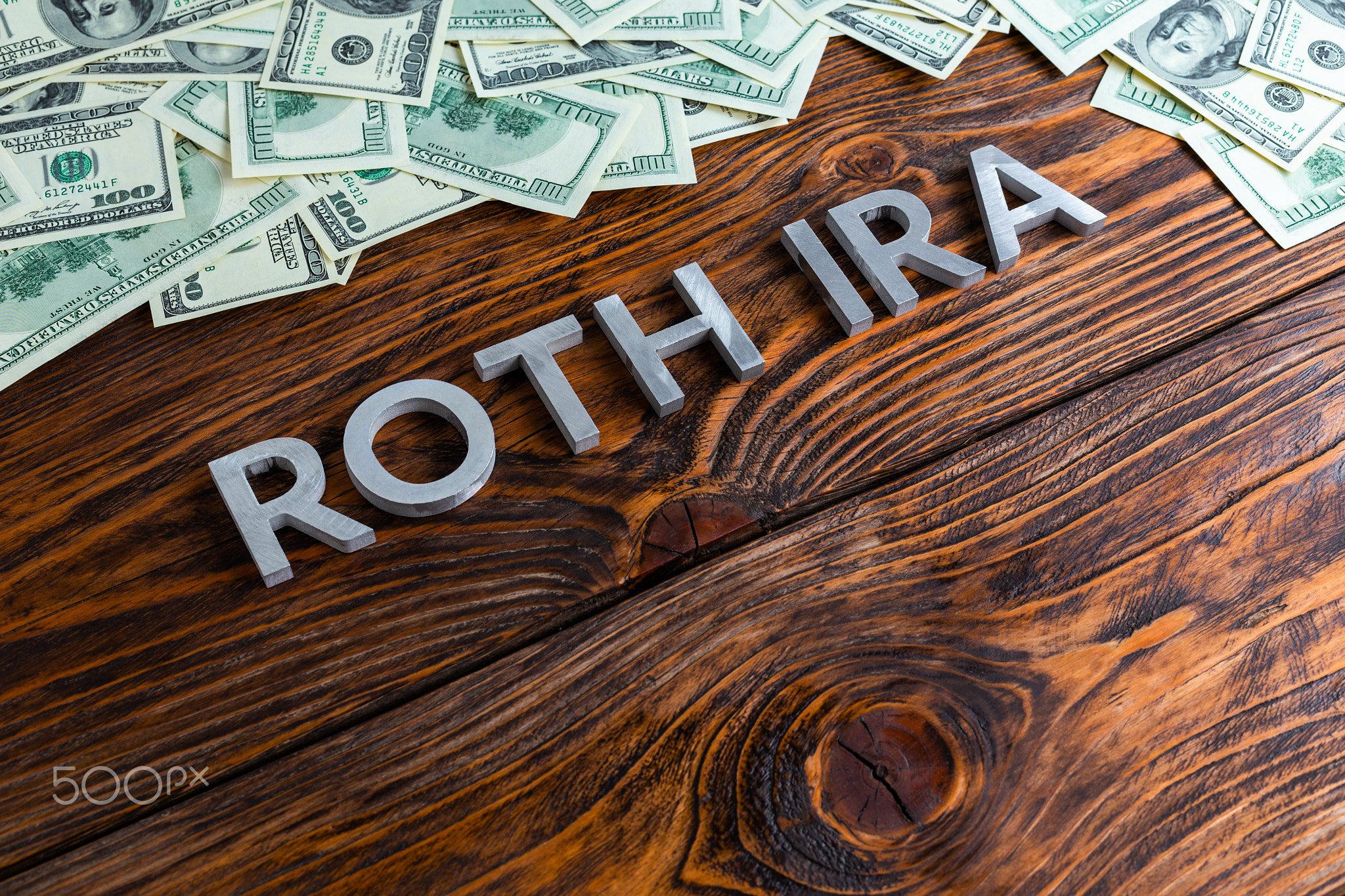 words ROTH IRA laid on wooden surface by metal letters with us dollar