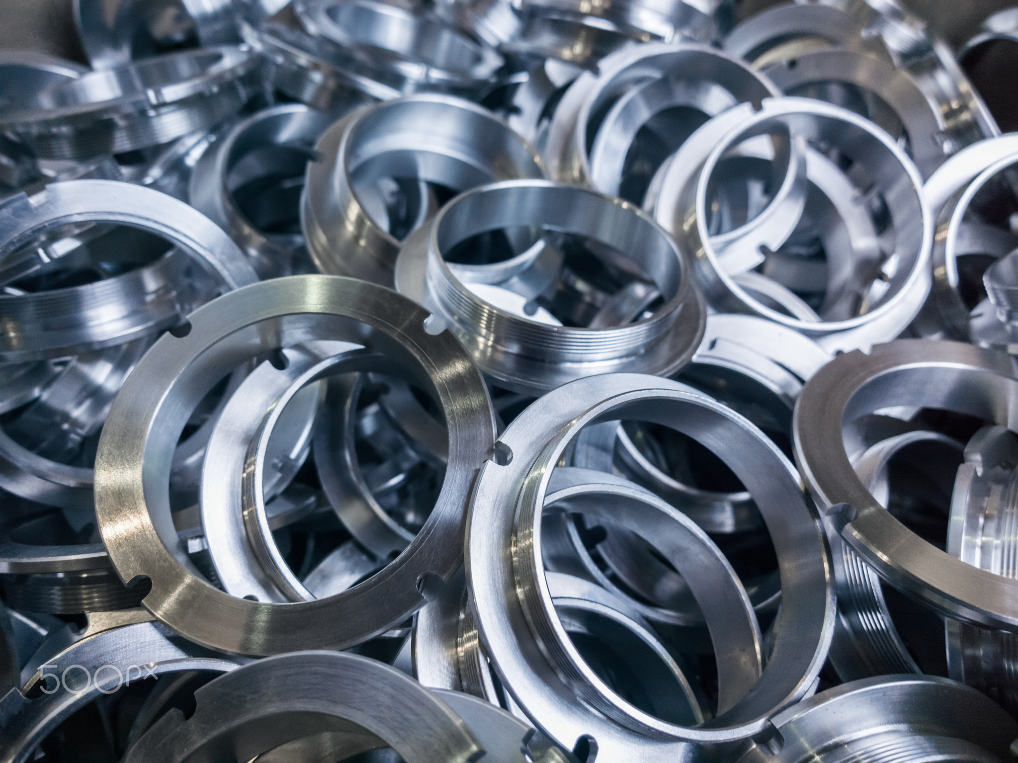 a batch of machined shiny metal parts with selective focus