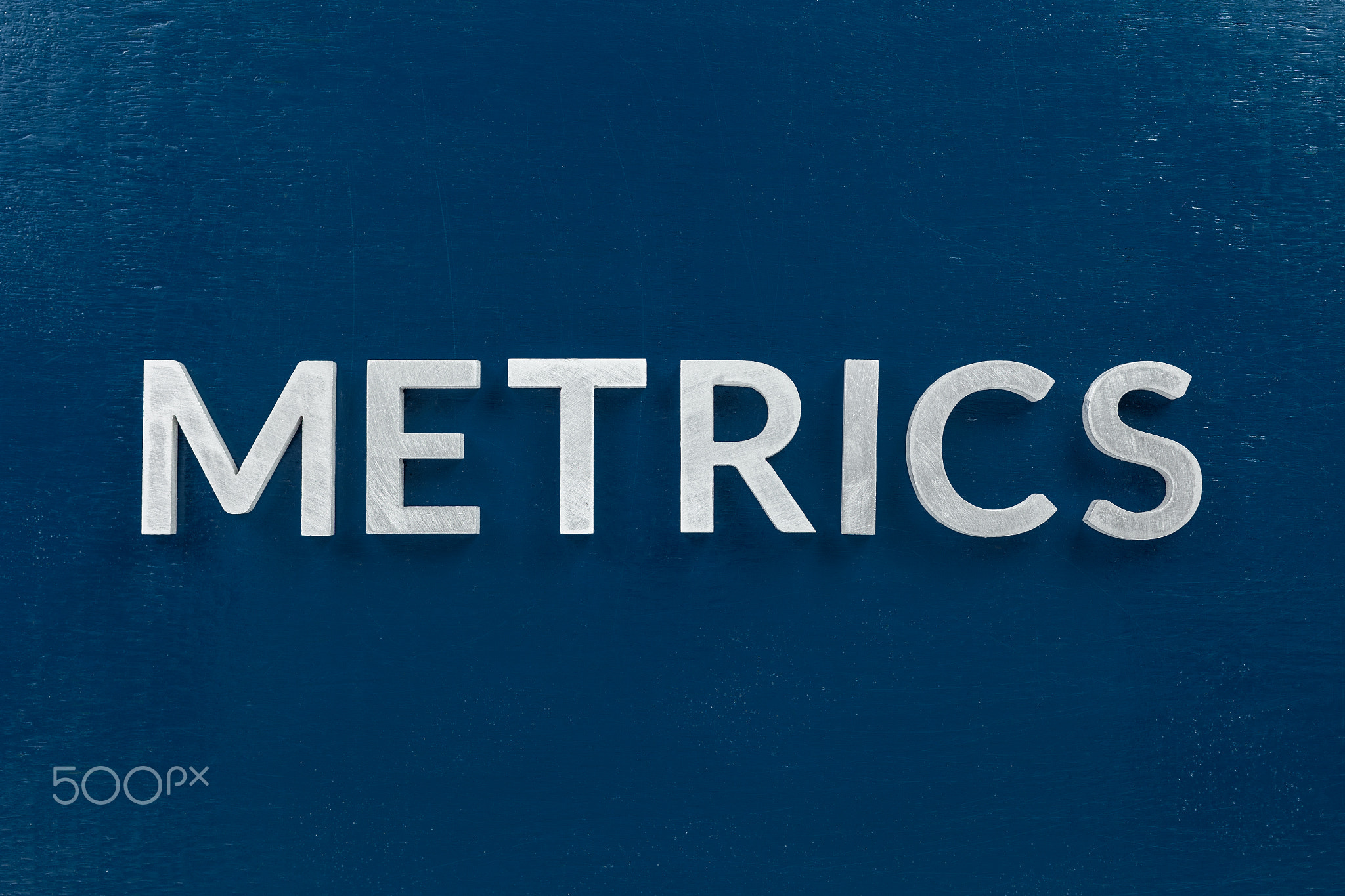 the word metrics laid with silver metal letters on classic blue