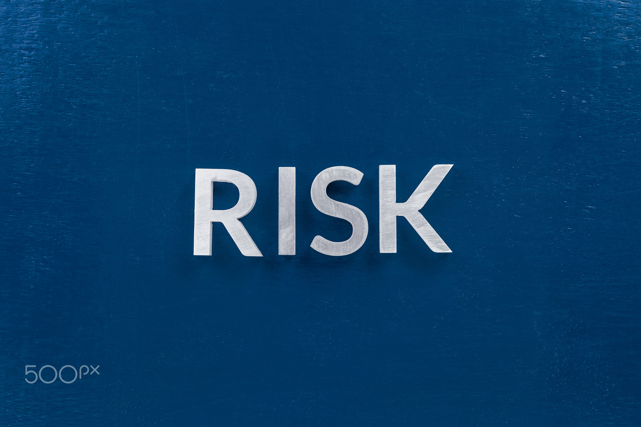 the words risk laid with silver metal letters on classic blue surface