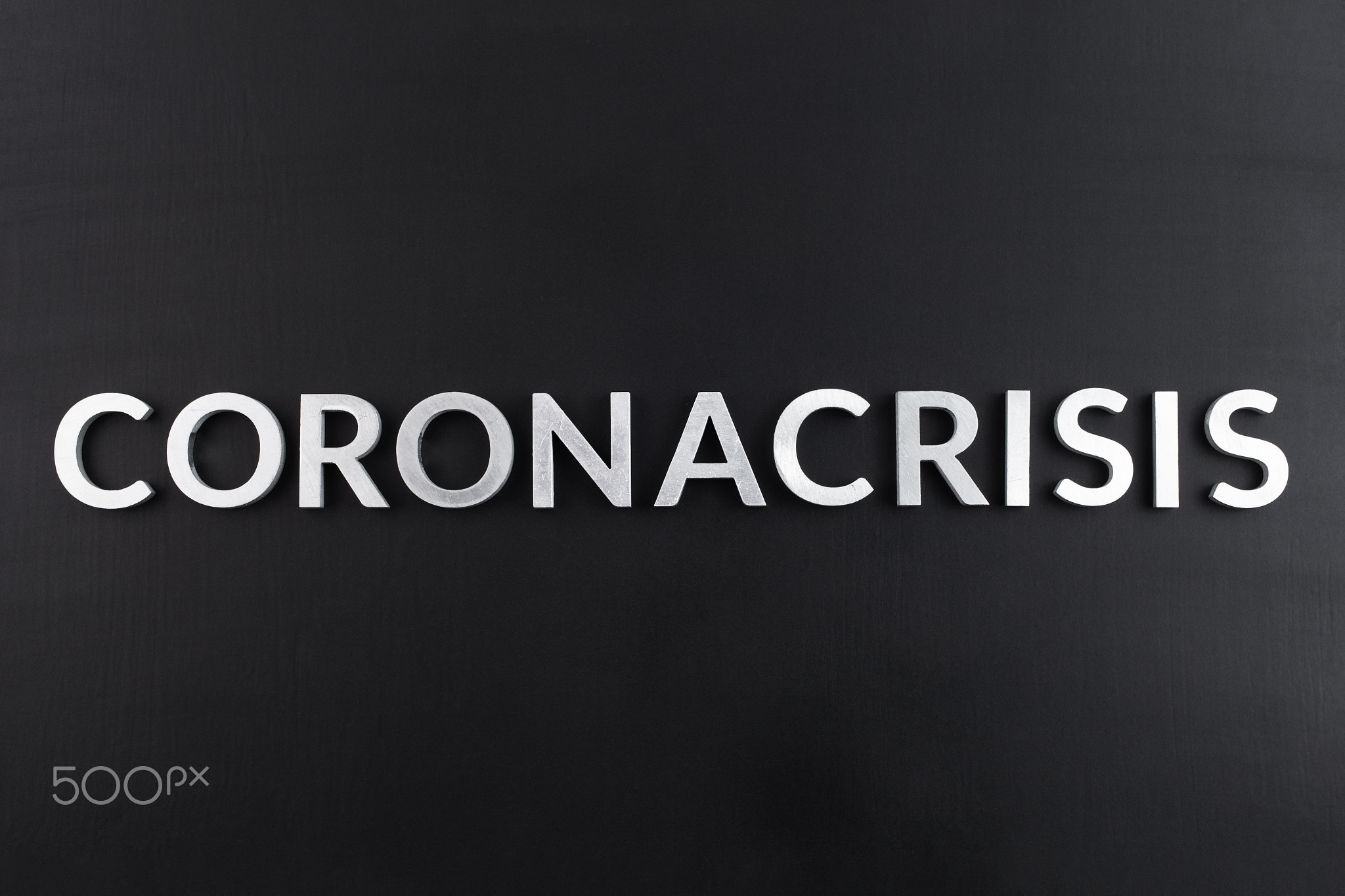 the word coronacrisis laid with white brushed metal letters on flat